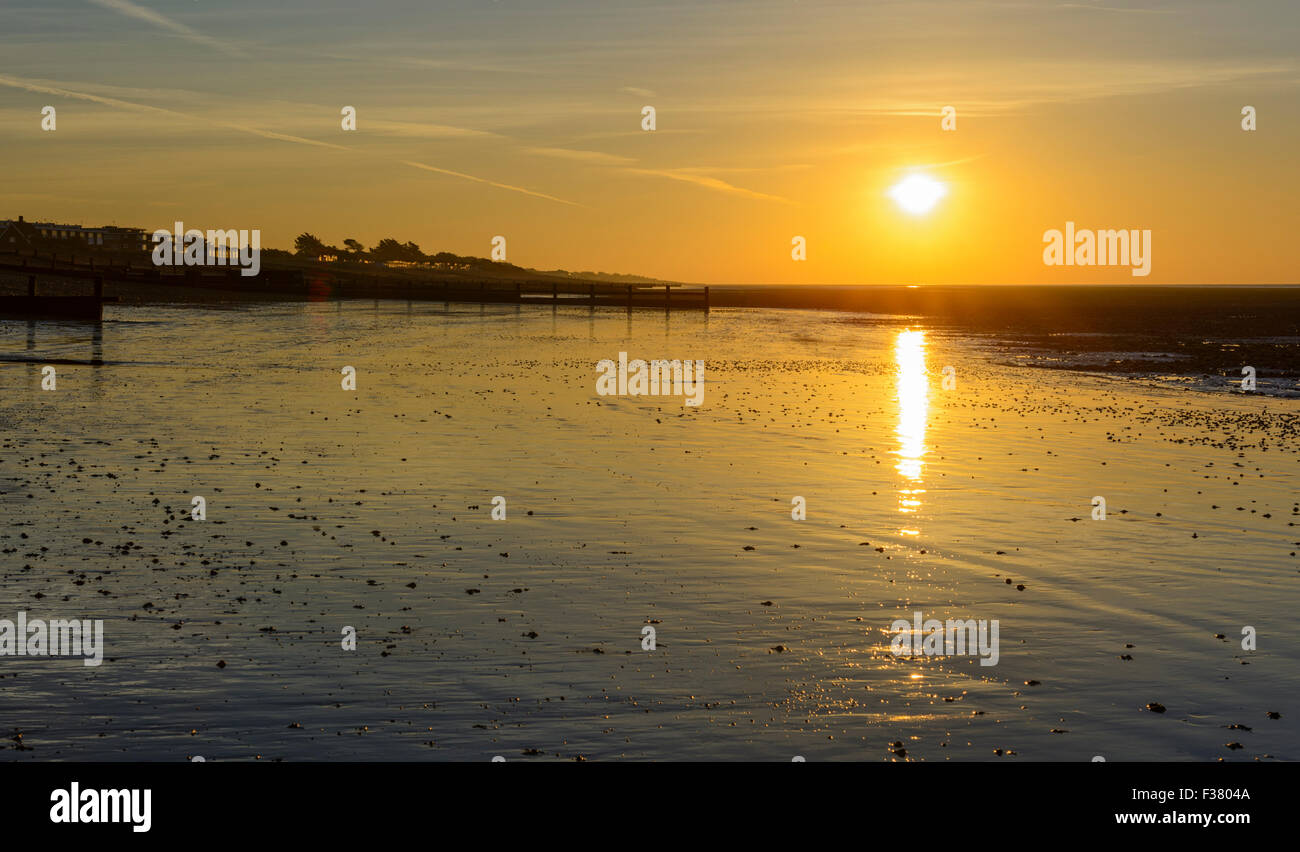 New Start. Sunrise over the beach at low tide, with the sun reflecting in the wet sand. Stock Photo