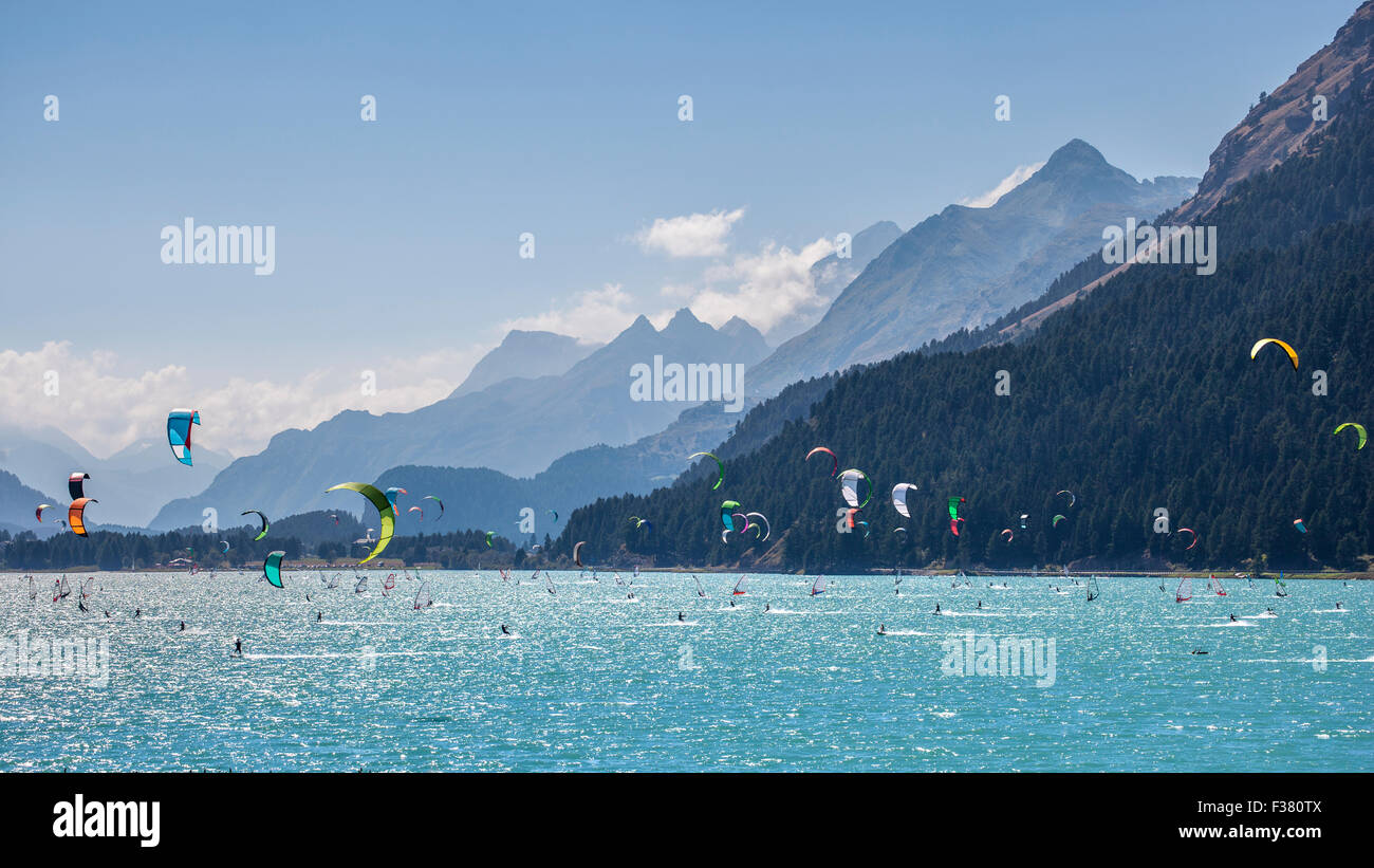 Mountain landscape with a lot of kite surfers and  windsurfers moving in a lake. They use the wind to move their boards on the w Stock Photo
