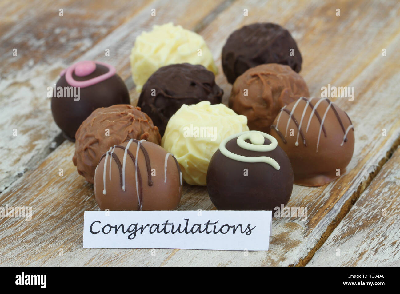 Congratulations card with assorted chocolates on rustic wooden surface Stock Photo