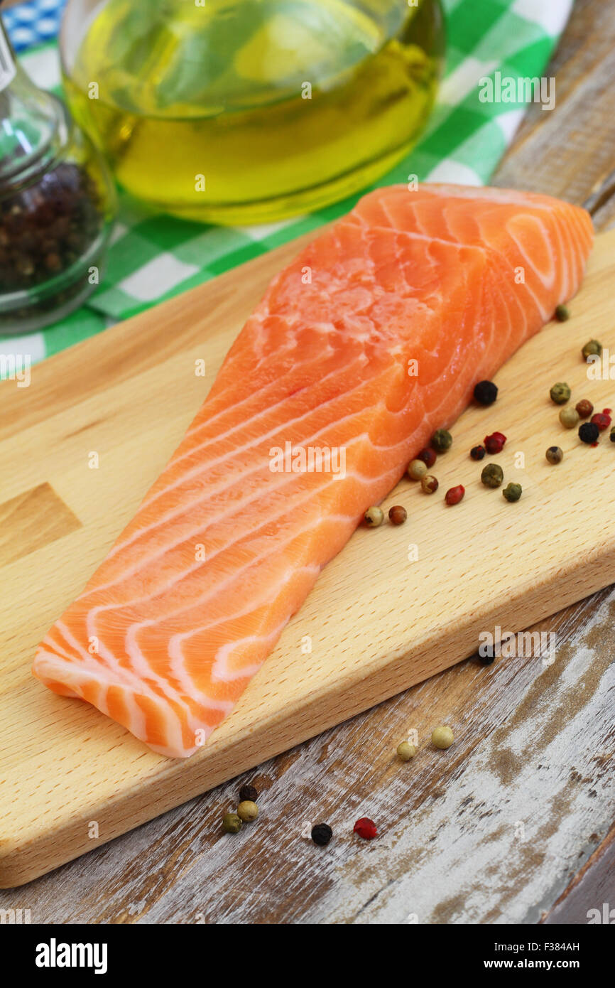 Raw salmon steak with black pepper on wooden board Stock Photo