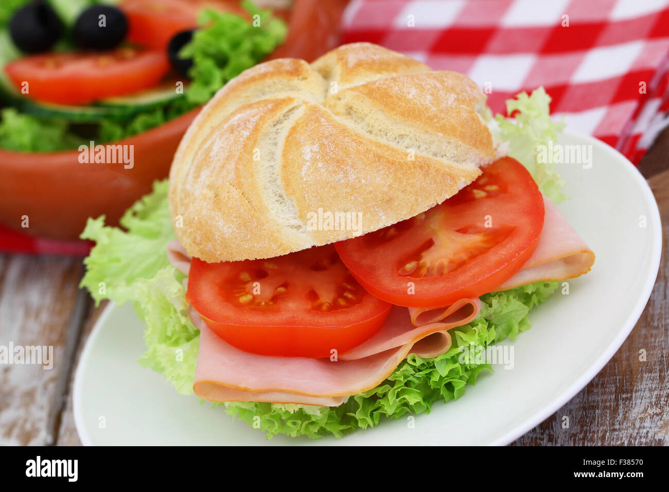 Bread roll with smoked ham, lettuce and tomatoes Stock Photo