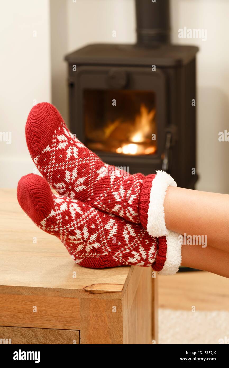 Woman warming feet in front of a cosy fire at Christmas time Stock Photo