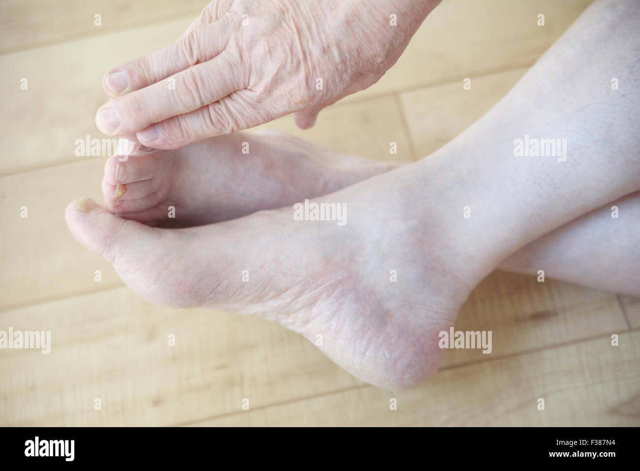 An older man reaches to touch his toes from a sitting position. Stock Photo