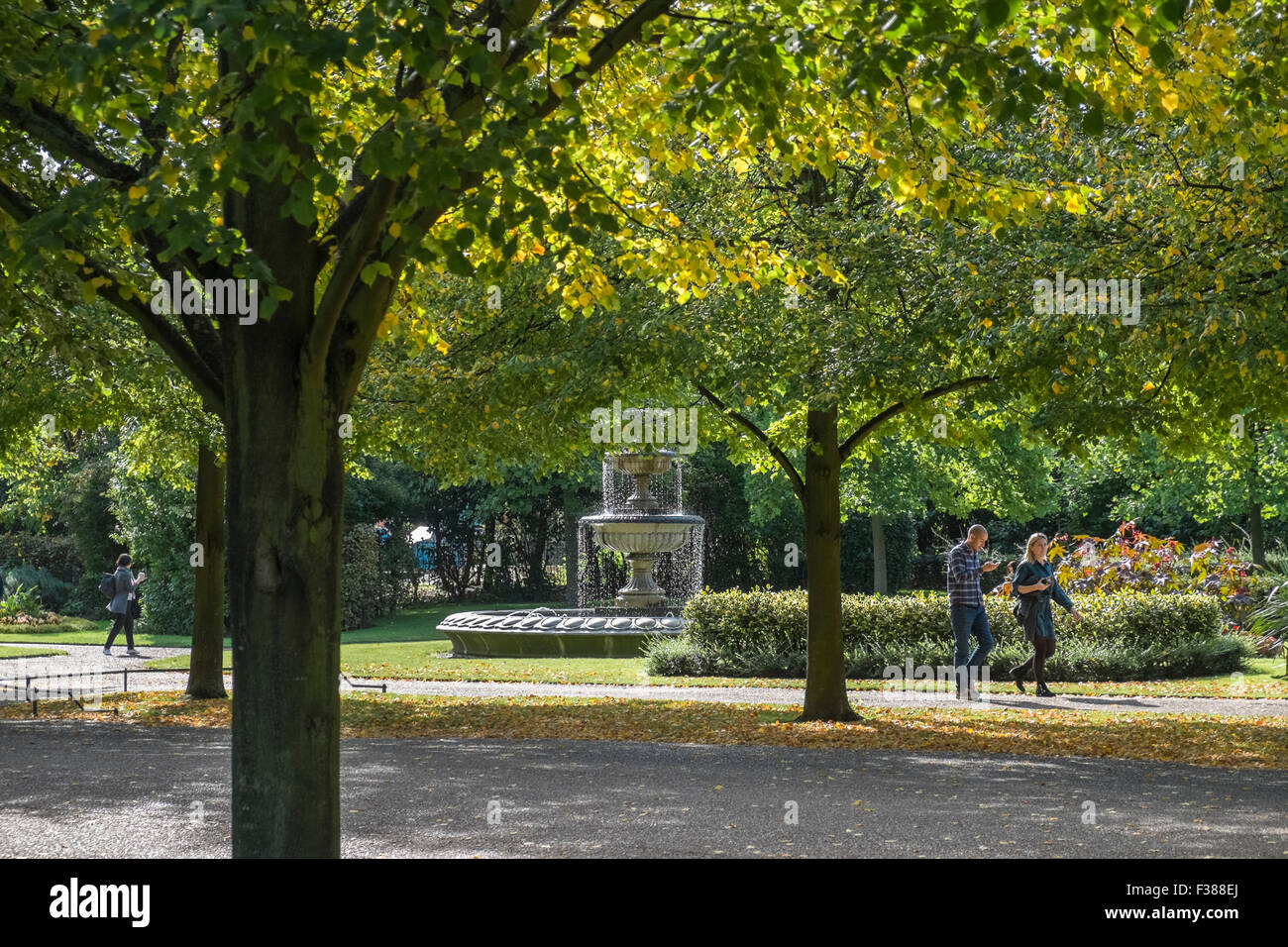 People walking through Regents Park enjoying the early autumn sunshine, London, England UK Stock Photo