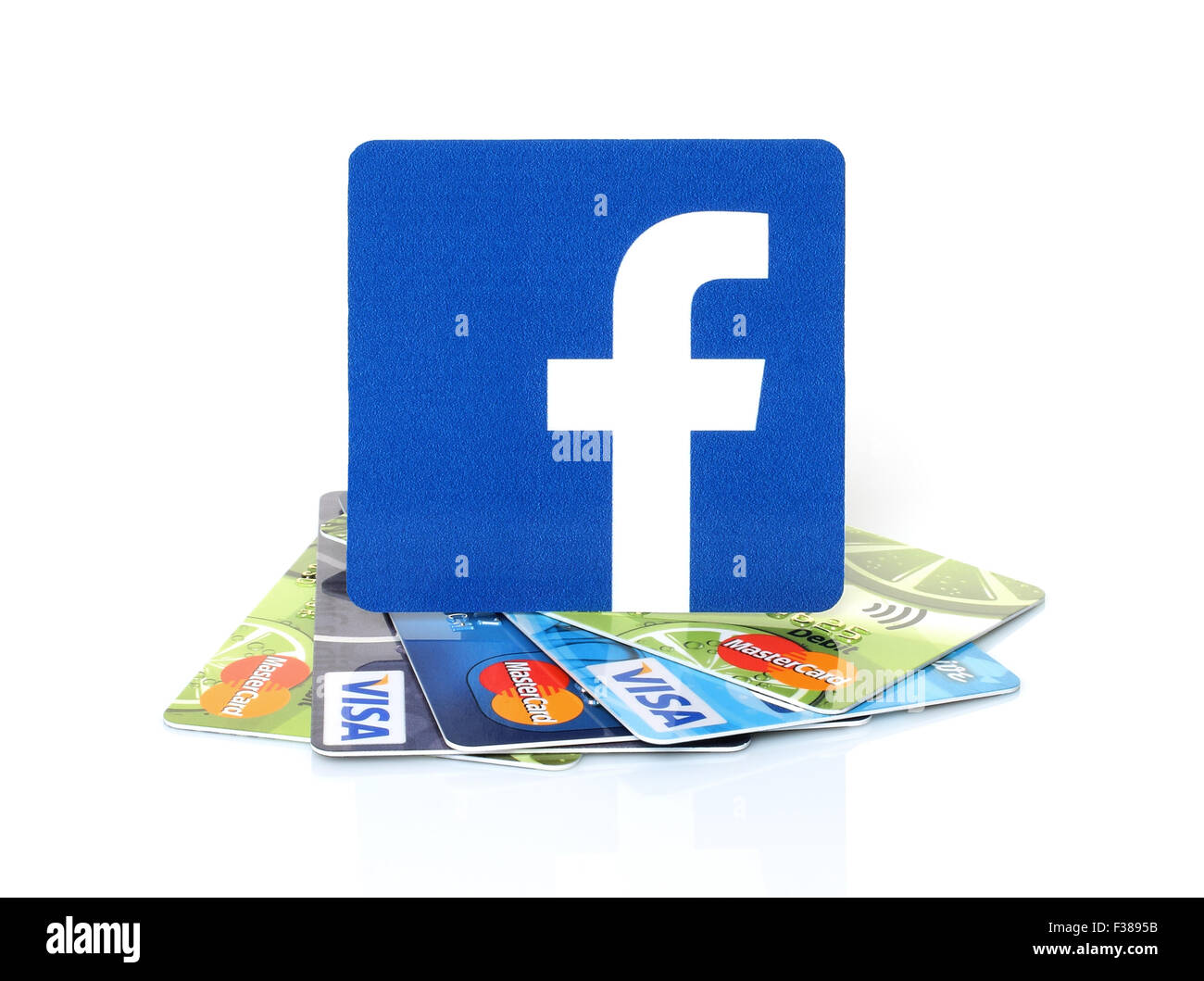 KIEV, UKRAINE - MARCH 21, 2015: Facebook logo printed on paper and placed on cards Visa and MasterCard on white background. Stock Photo