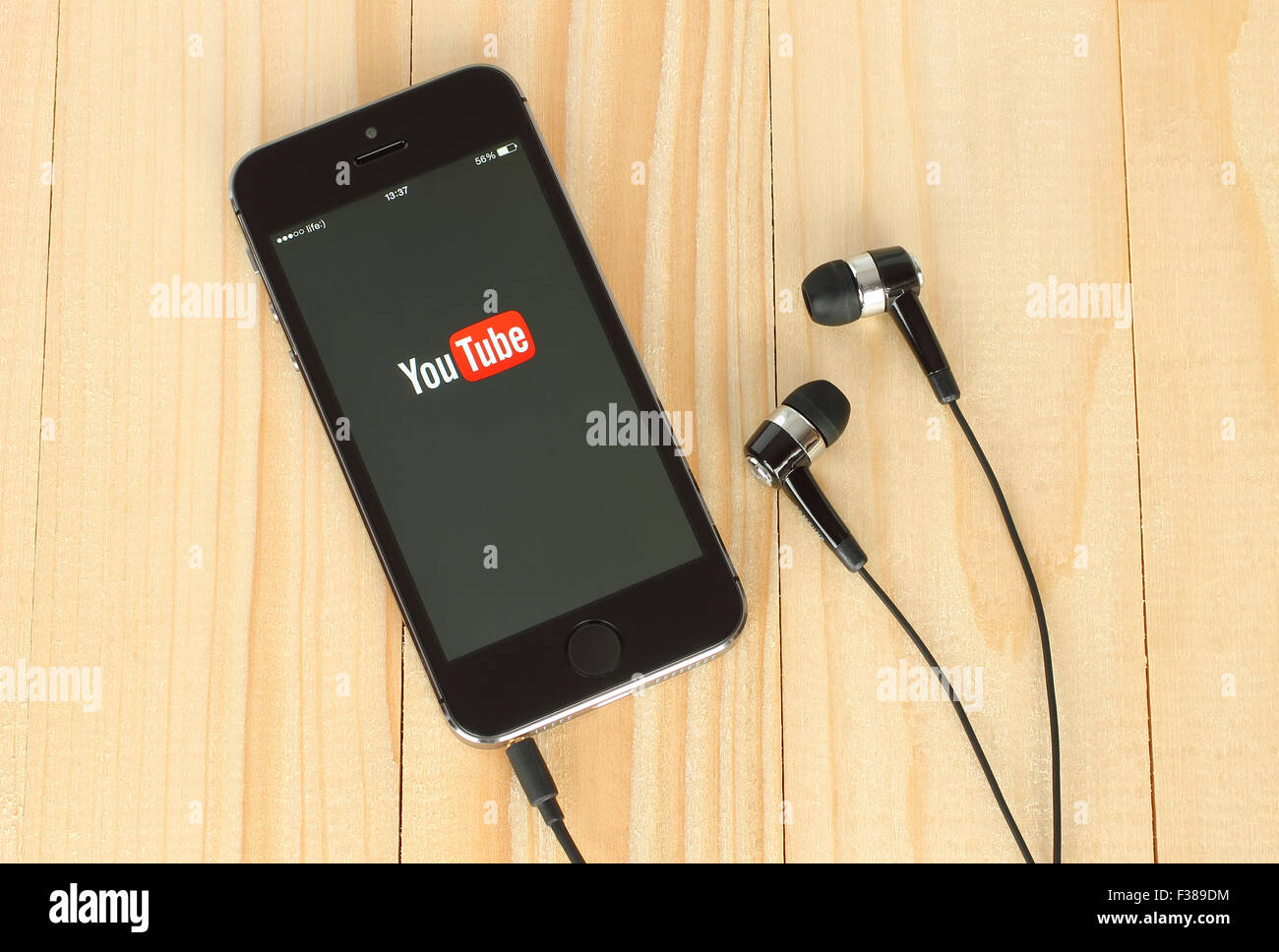 KIEV, UKRAINE - MAY 22, 2015: Smart phone with YouTube logo on its screen and headphones on wooden background Stock Photo