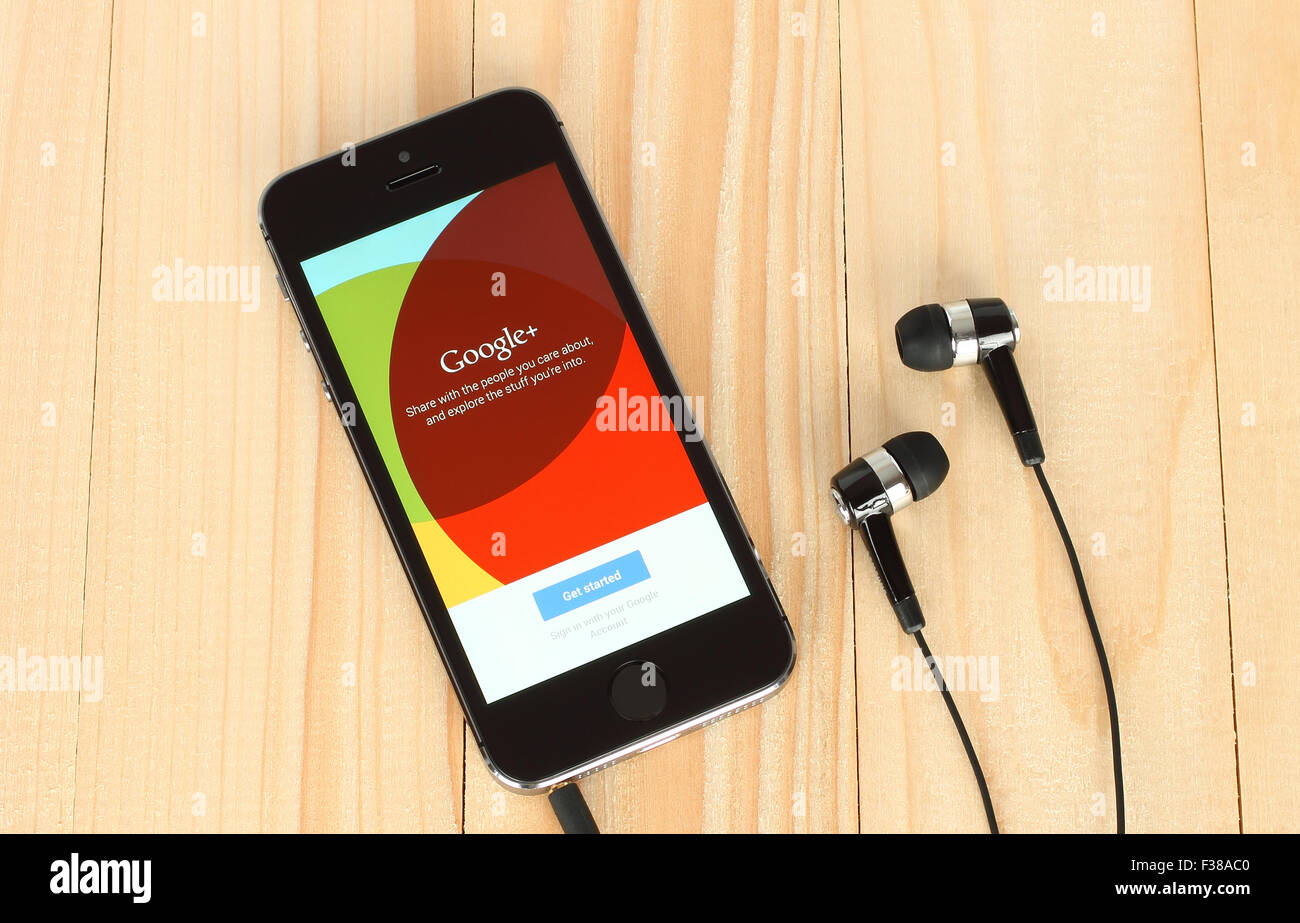 KIEV, UKRAINE - MAY 22, 2015:iPhone with Google Plus logotype on its screen and headphones on wooden background Stock Photo