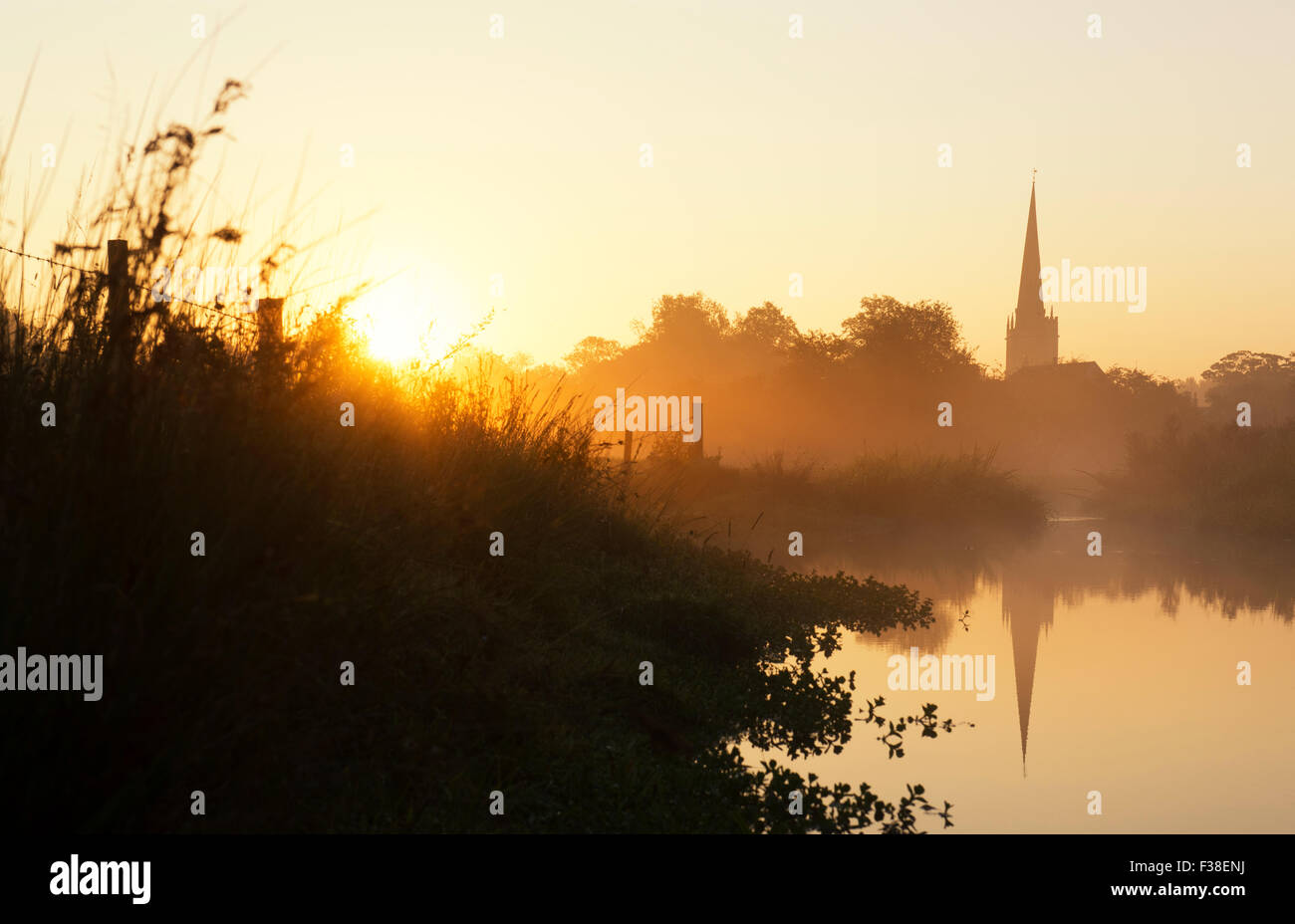 Burford Church reflected in the river windrush at sunrise in autumn. Burford, Cotswolds, Oxfordshire, England Stock Photo