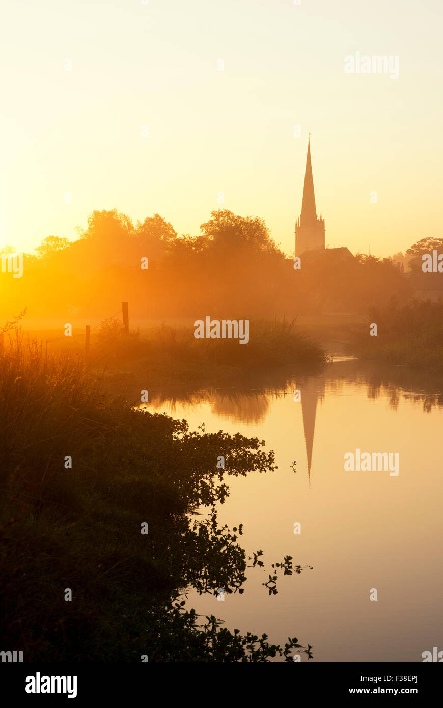 Burford Church reflected in the river windrush at sunrise in autumn. Burford, Cotswolds, Oxfordshire, England Stock Photo