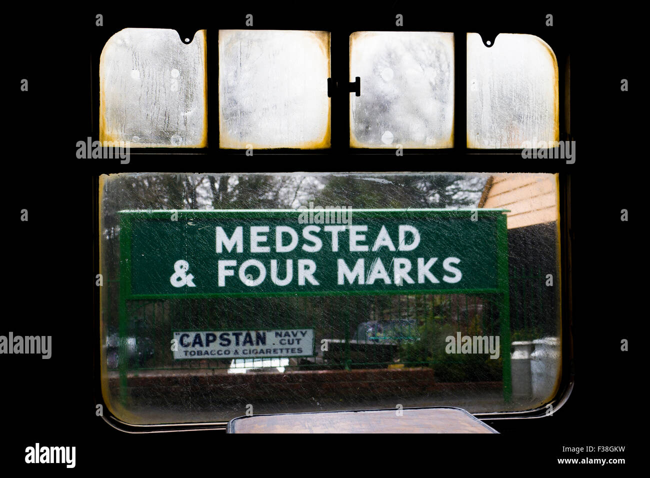 Looking through carriage window at station sign in steam and rain at Medstead & Four Marks station on The Mid Hants Heritage Rai Stock Photo