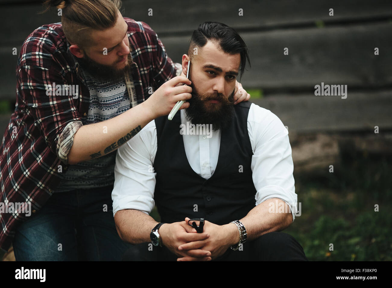 barber shaves a bearded man Stock Photo