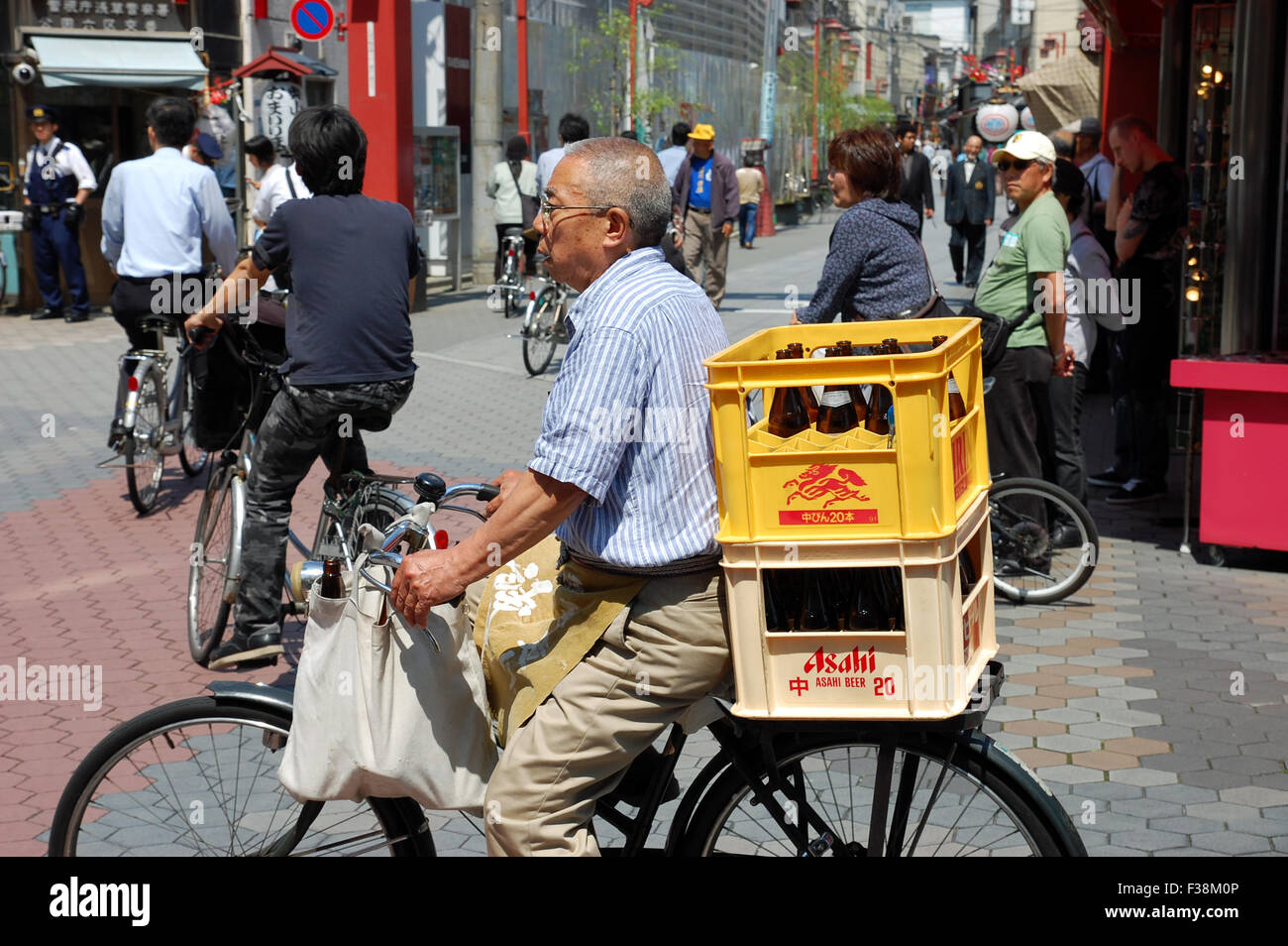 Japanese man on a bicycle transporting beer in crates in the Asakusa Ward of Tokyo, Japan. Stock Photo