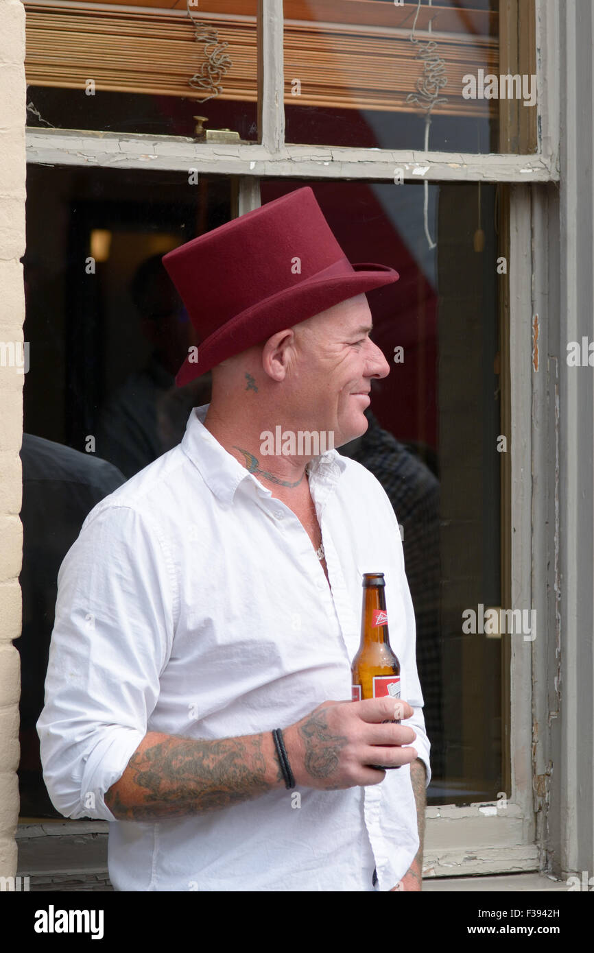 Man wearing red top hat drinking a beer outside pub in Bedford
