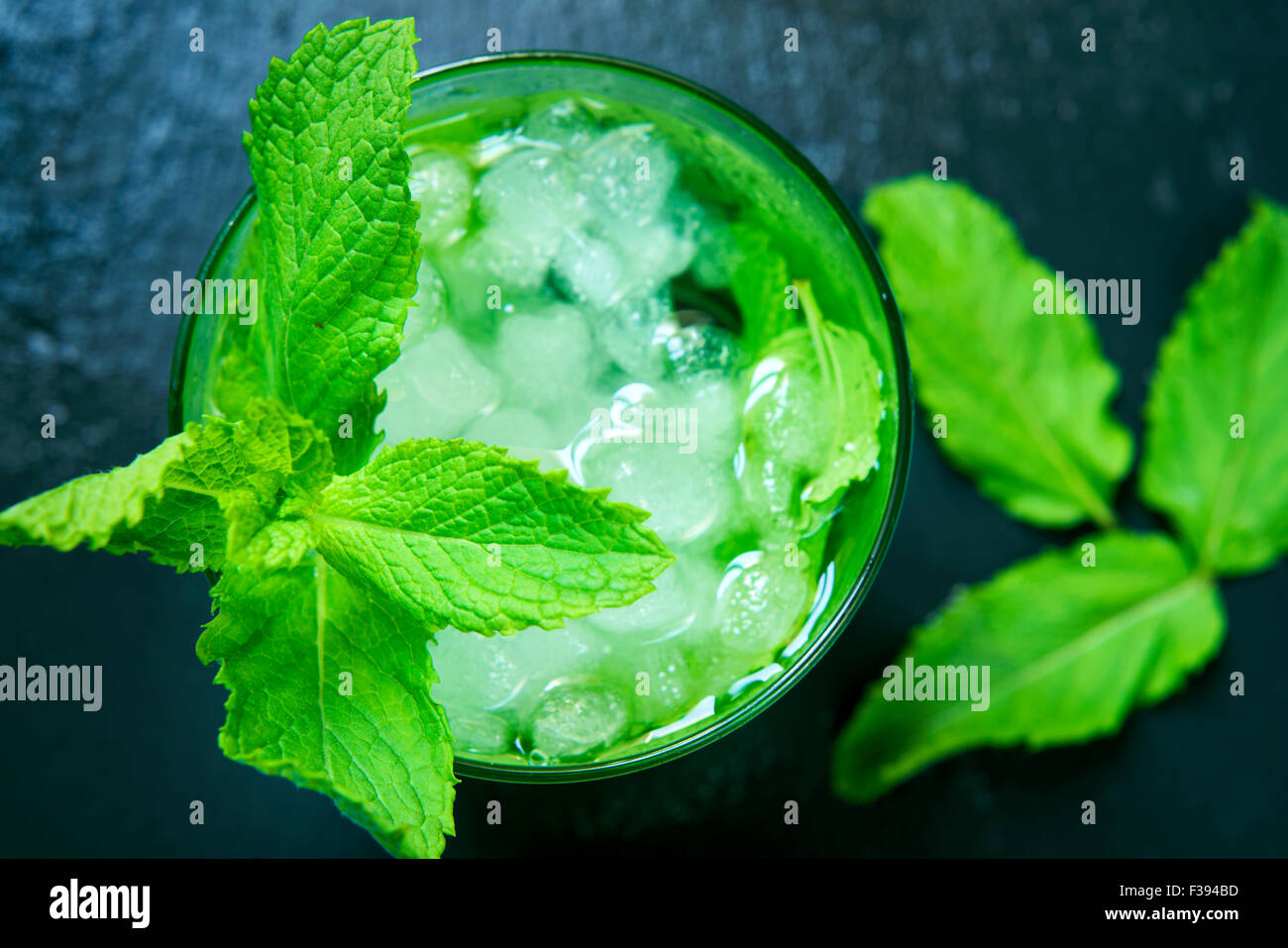 high-angle shot of a glass with an appetizing mojito garnished with a twig of mint on a black slate background Stock Photo