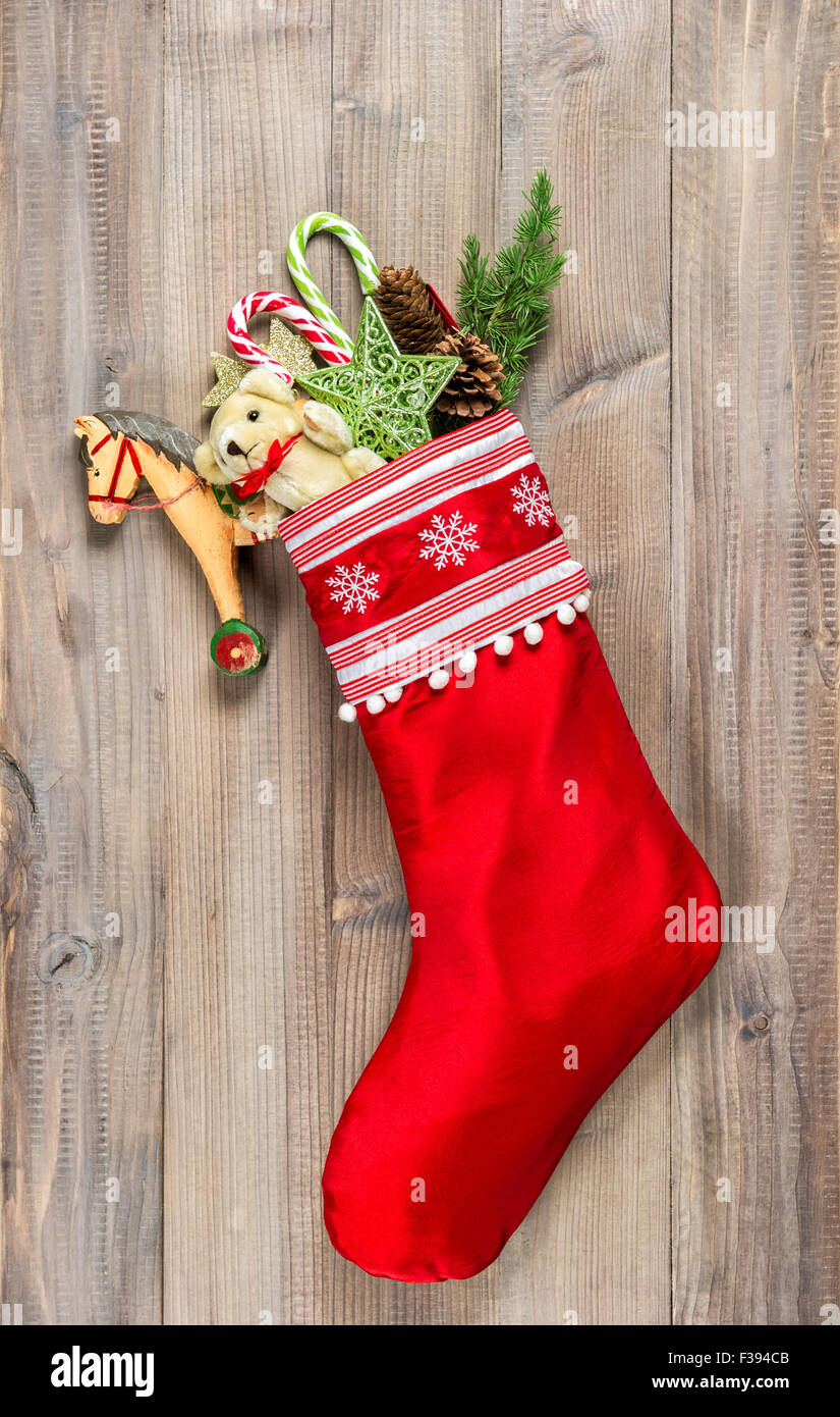 Christmas stocking with nostalgic vintage toys decoration and pine branch over wooden background Stock Photo