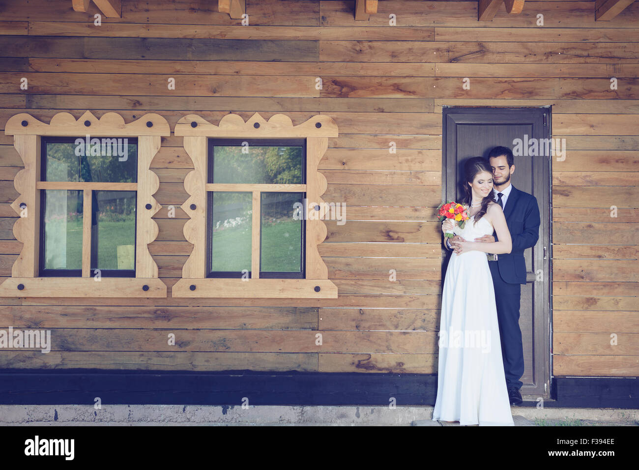 Bride and groom in front of house golding togher. Just married young ...