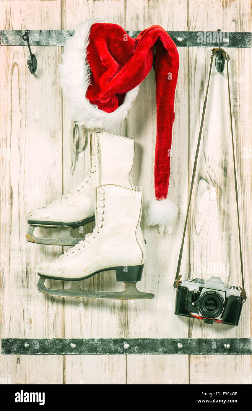 Christmas decoration. Red Santas hat, retro photo camera and white ice skates. Vintage style toned picture Stock Photo
