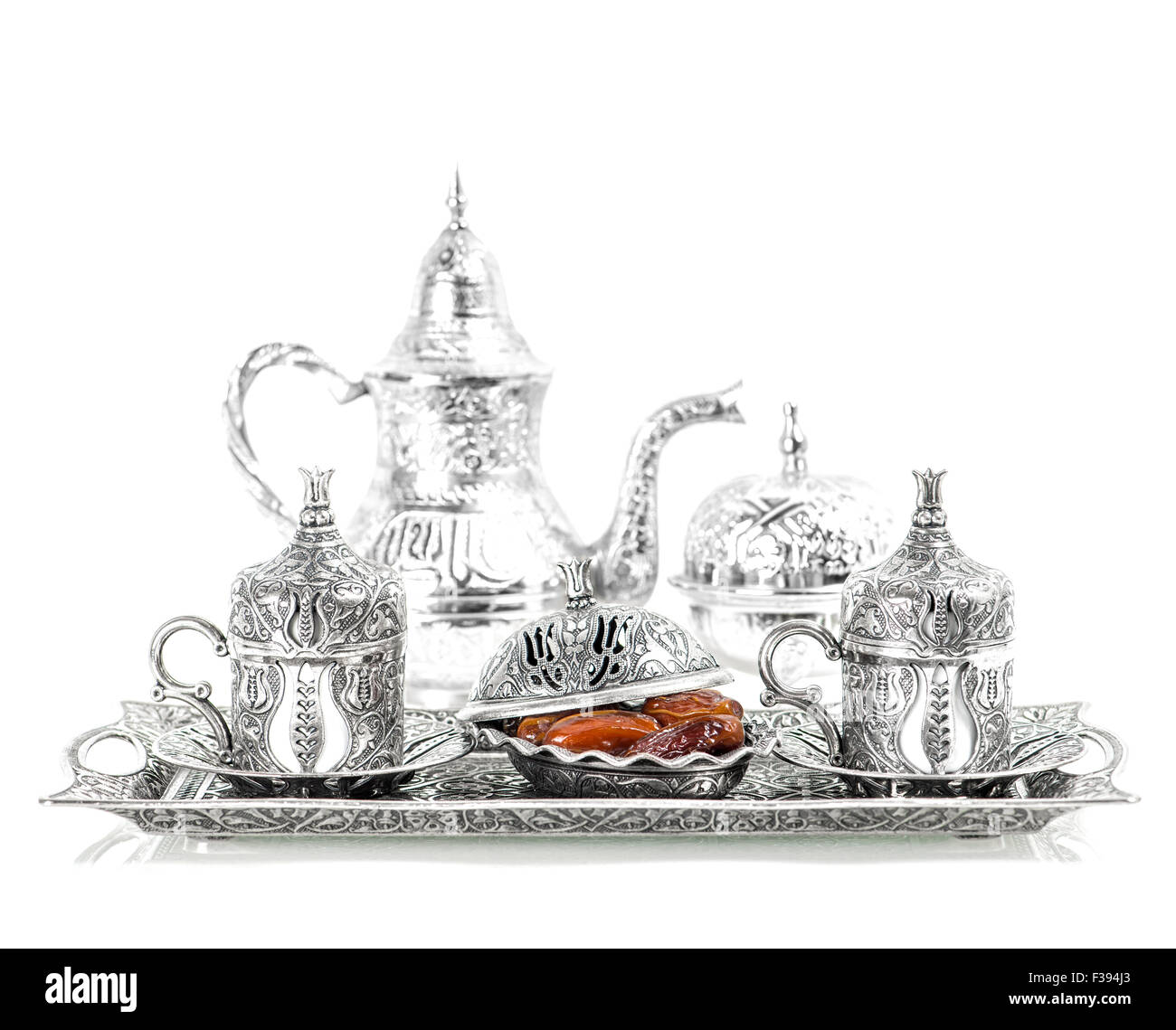 Table setting with silver tableware and dates. Oriental hospitality concept with tea or coffee cups. High key picture Stock Photo