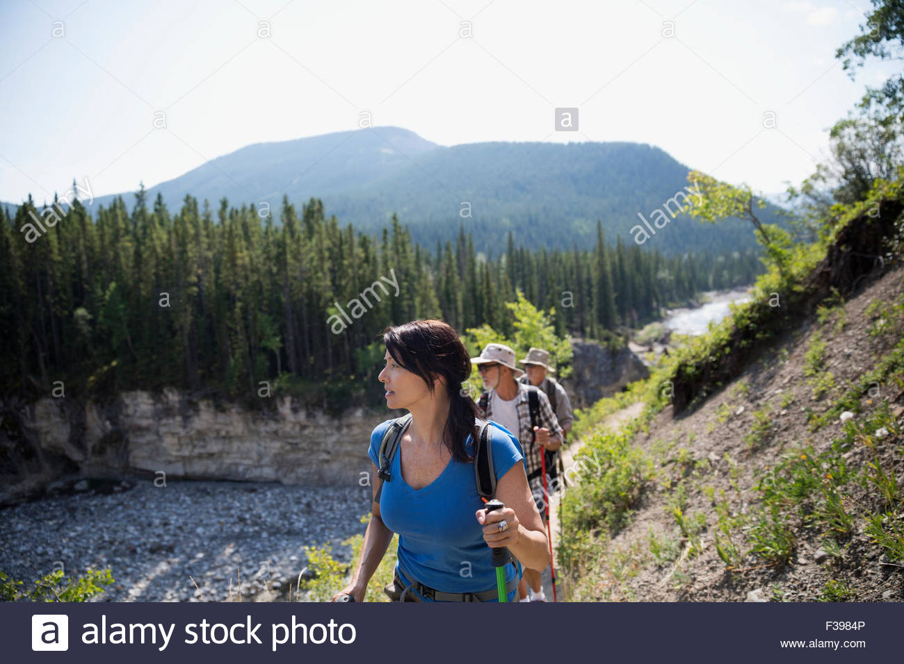 Hikers walking along craggy ridge above river Stock Photo