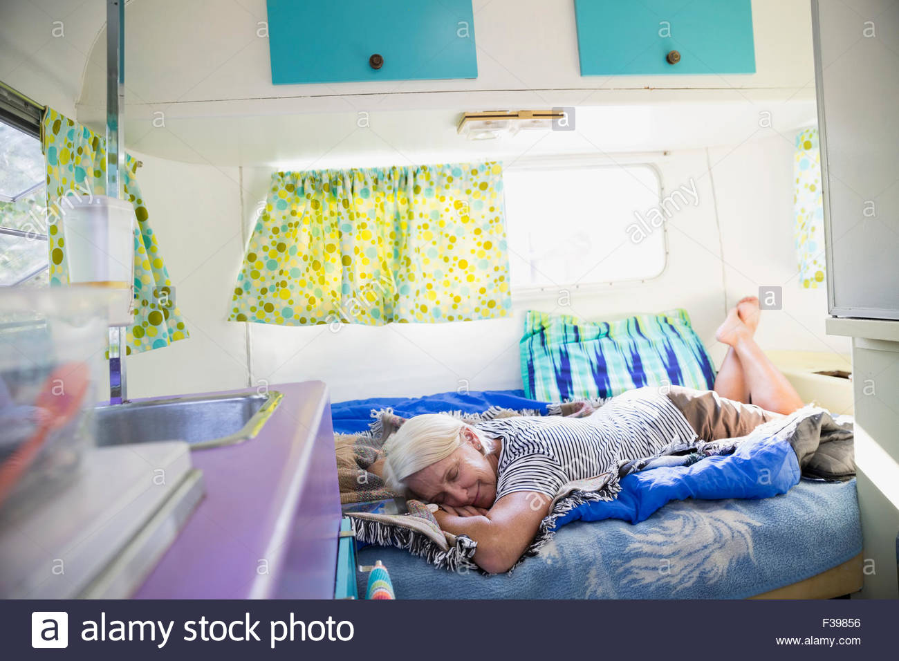 Senior woman napping on bed in camper trailer Stock Photo