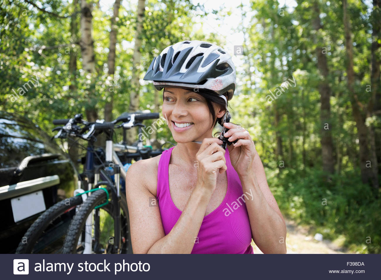 Smiling woman fastening mountain biking helmet Stock Photo
