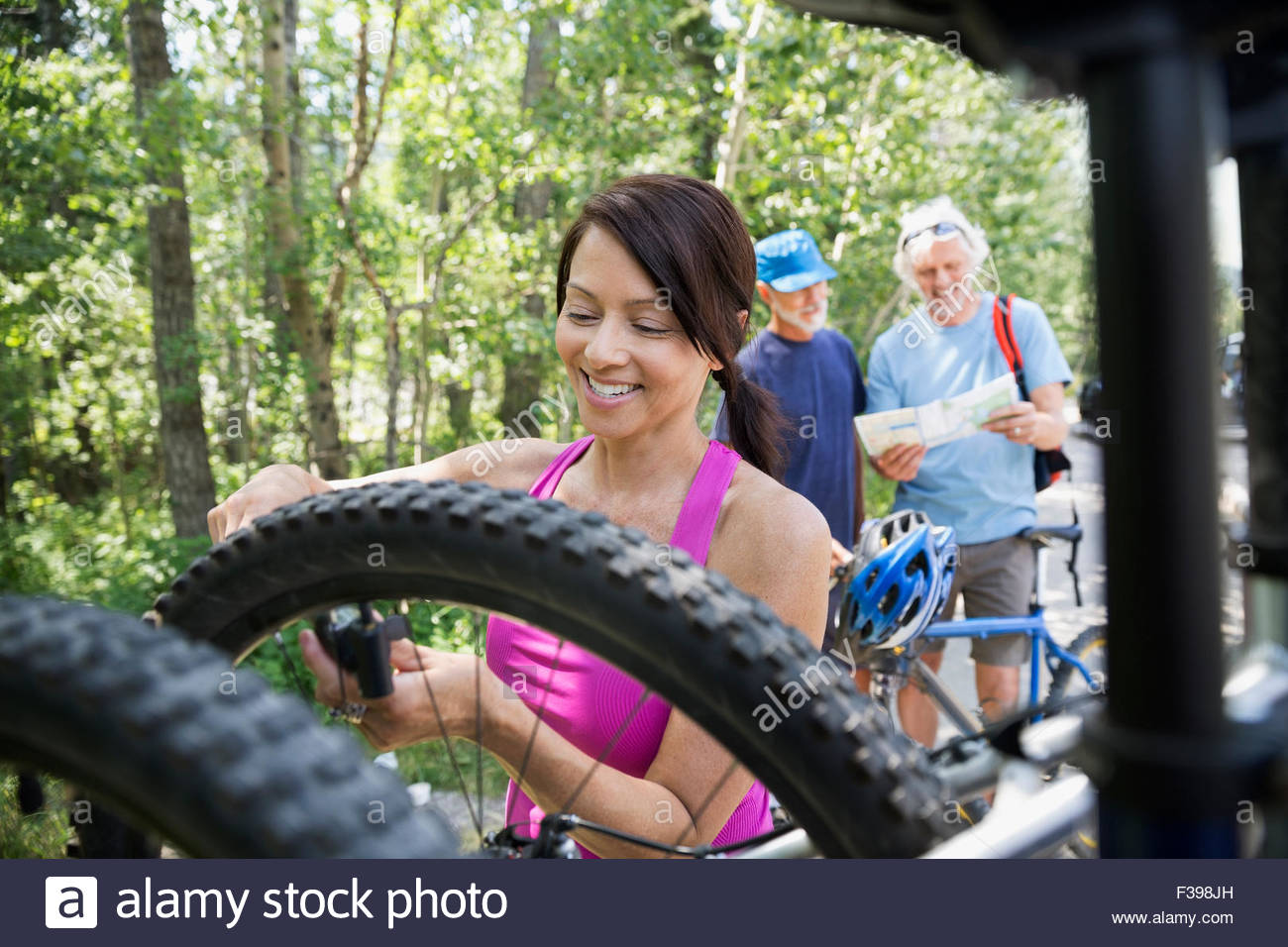 Smiling woman removing mountain bike from rack Stock Photo