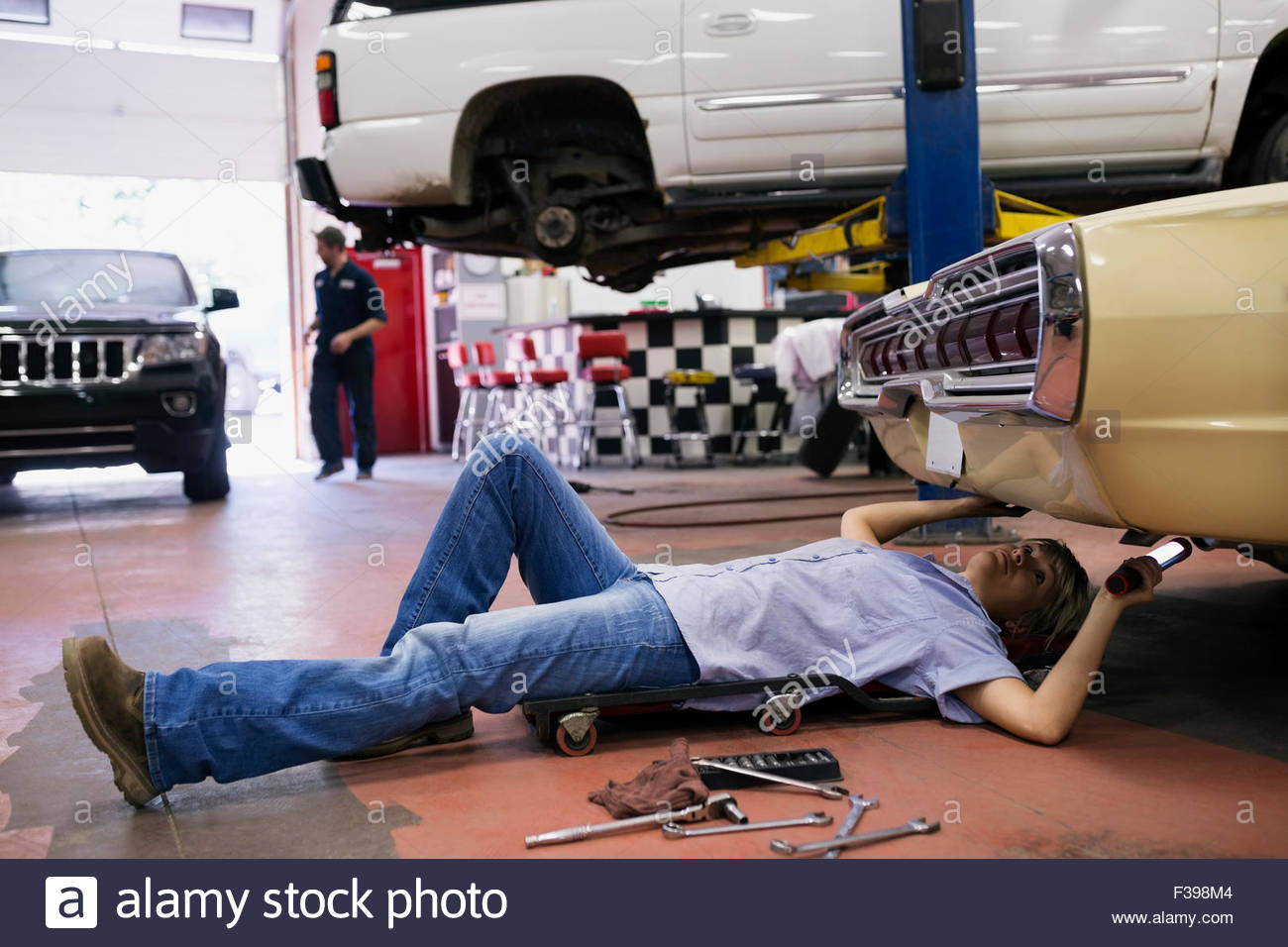 Female mechanic underneath car in auto repair shop Stock Photo - Alamy