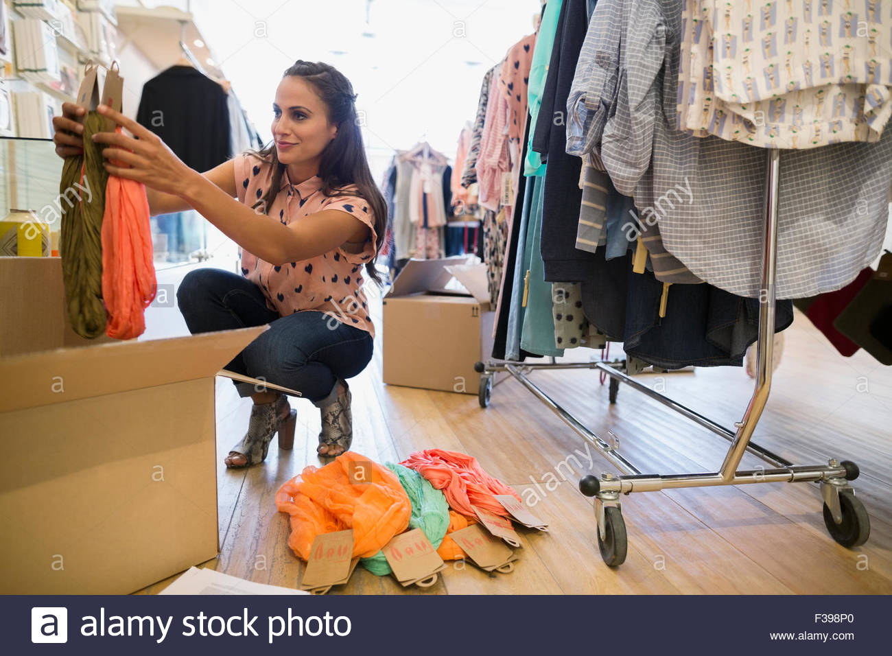 Business owner unpacking new inventory in clothing shop Stock Photo