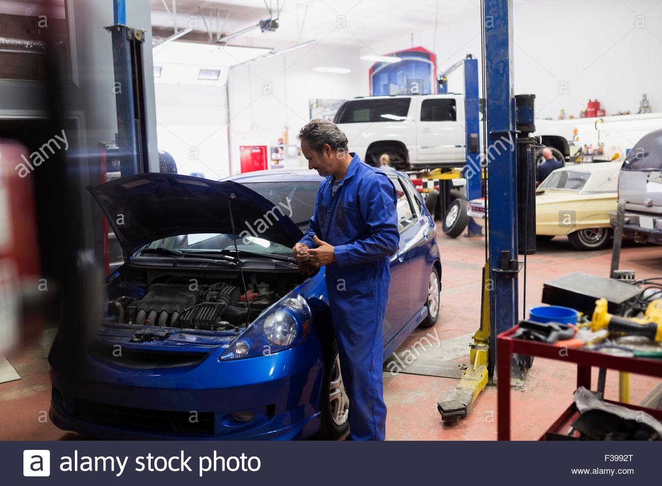 Mechanic looking down at engine auto repair shop Stock Photo
