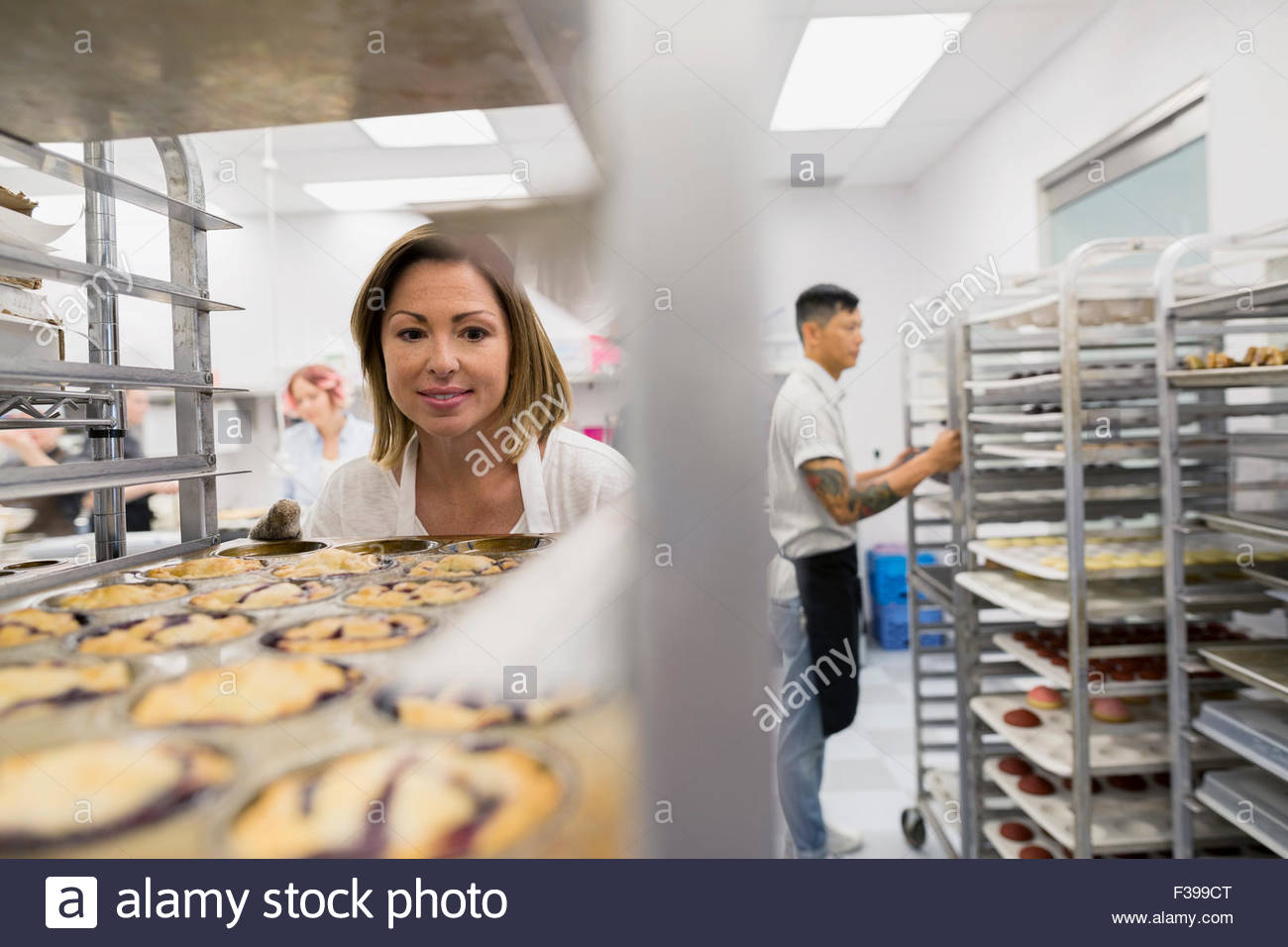 Pastry chef placing muffin tray on rack Stock Photo