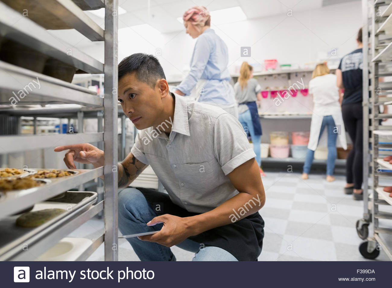 Pastry chef counting muffins on racks commercial kitchen Stock Photo