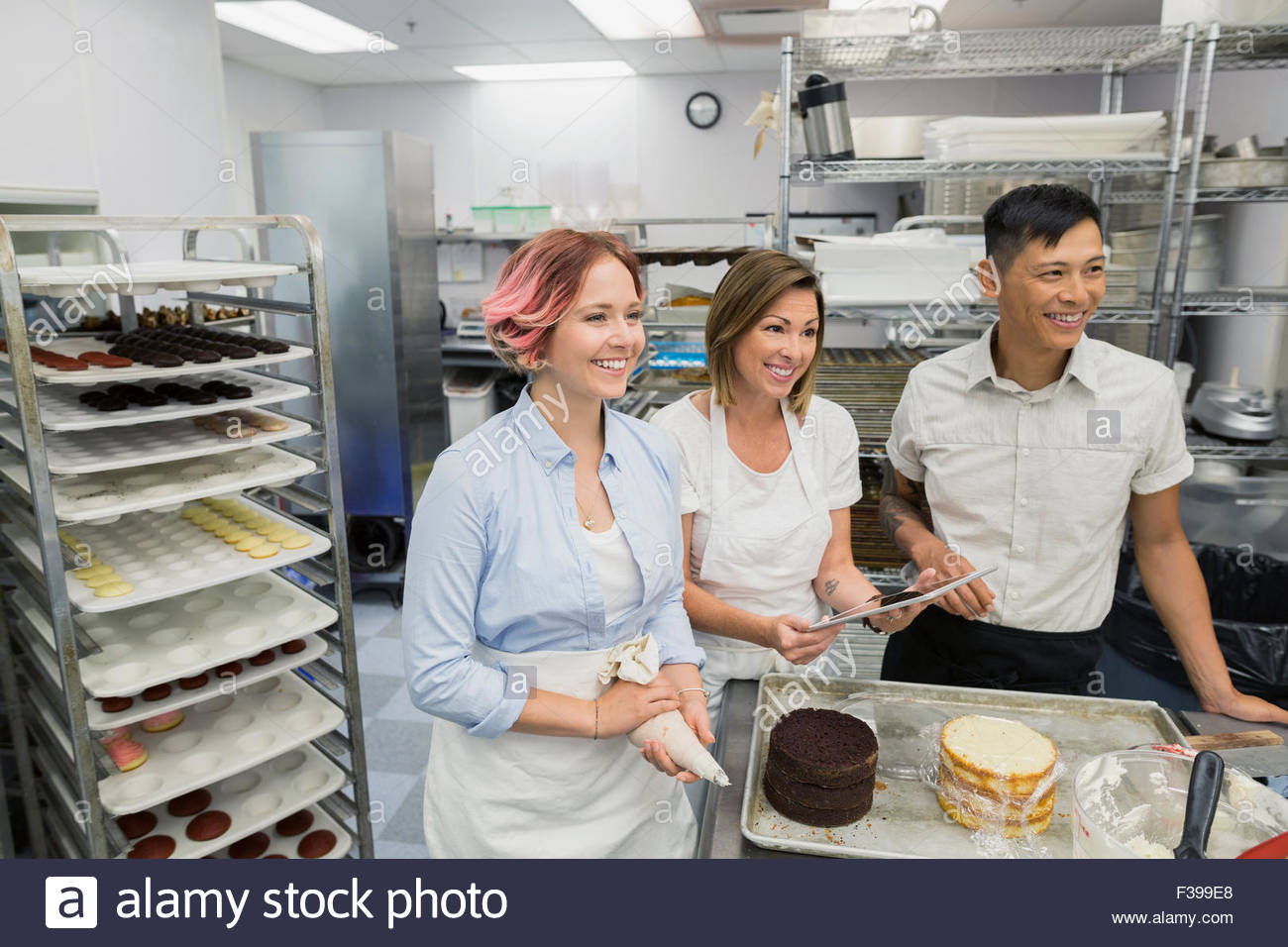 Smiling pastry chefs digital tablet in commercial kitchen Stock Photo