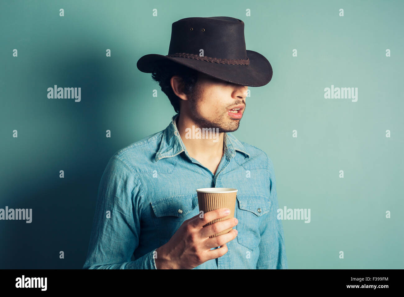 Young cowboy is drinking coffee from a paper cup Stock Photo Alamy
