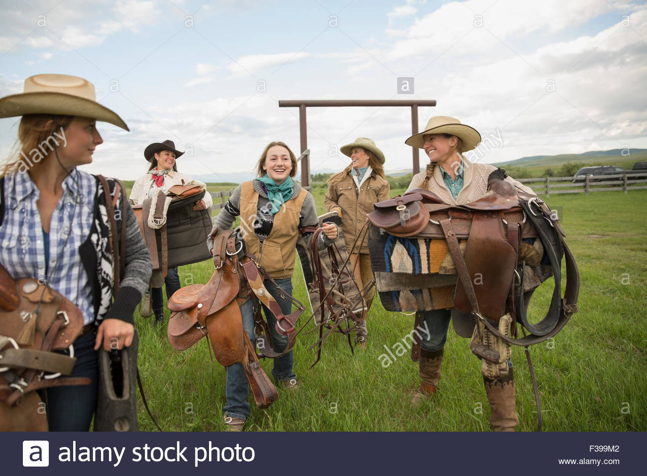 Female ranchers carrying saddles in rural pasture Stock Photo Alamy