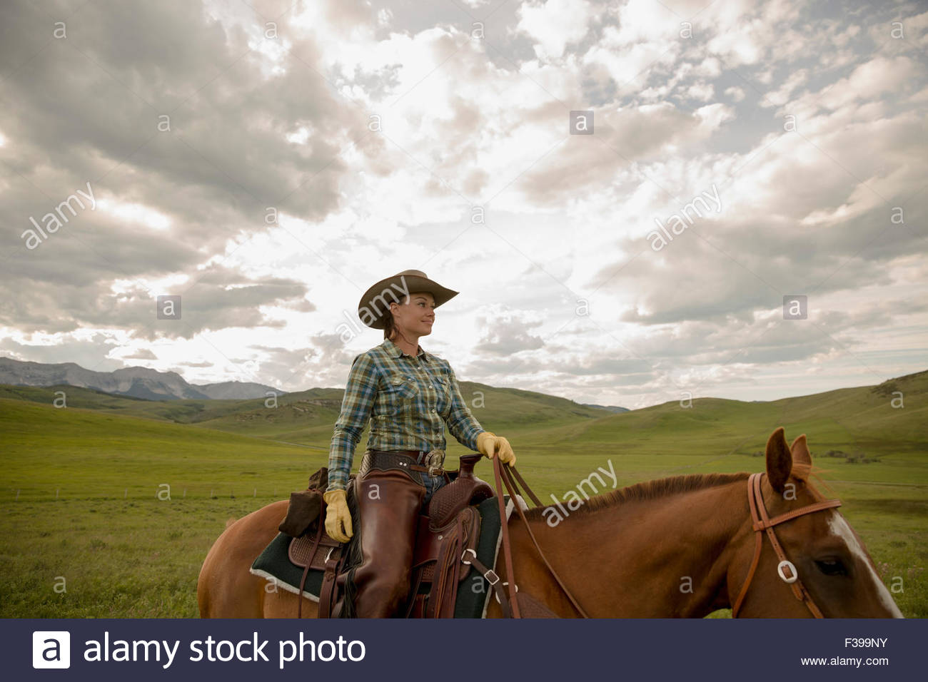 Female rancher riding horse in remote field Stock Photo Alamy