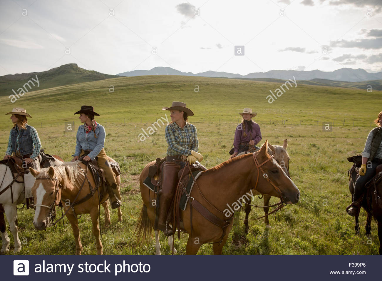 Female ranchers on horseback in sunny remote field Stock Photo