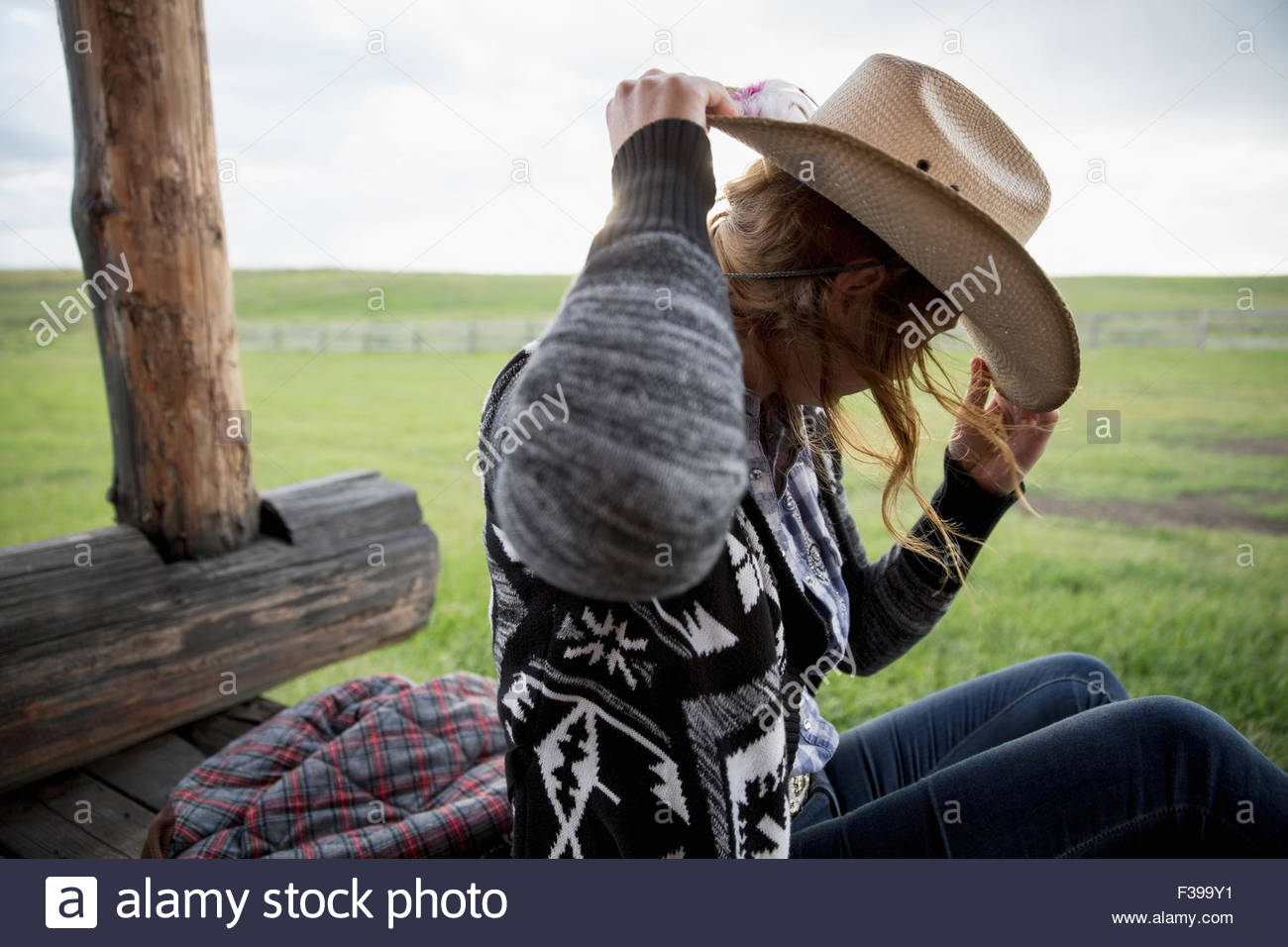 Female rancher adjusting cowboy hat on porch Stock Photo