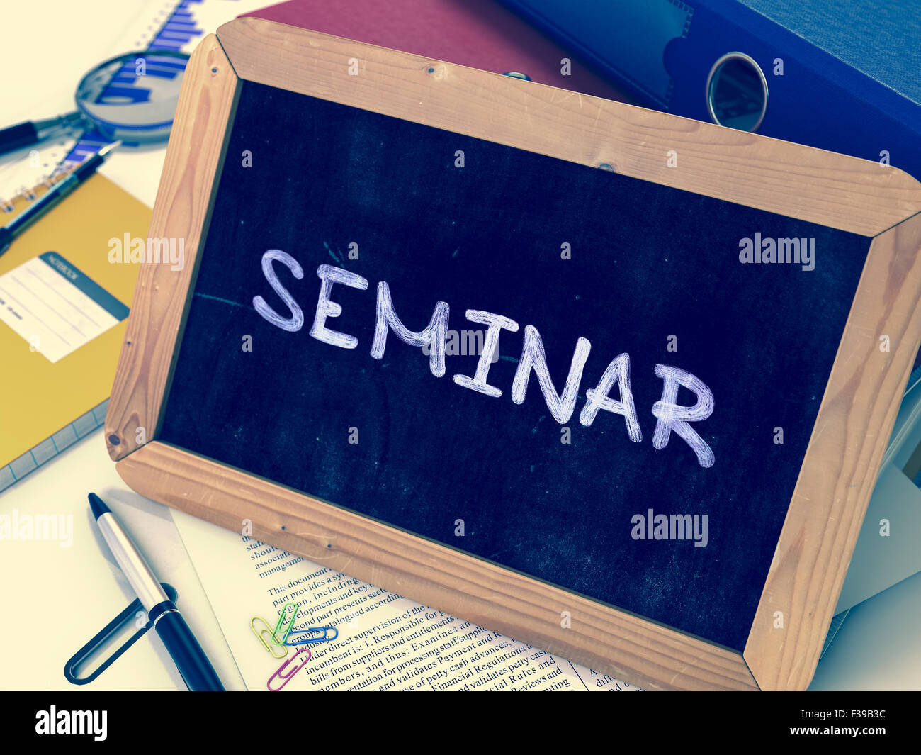Seminar - Handwritten by white Chalk on a Blackboard. Composition with Small Chalkboard on Background of Working Table with Offi Stock Photo