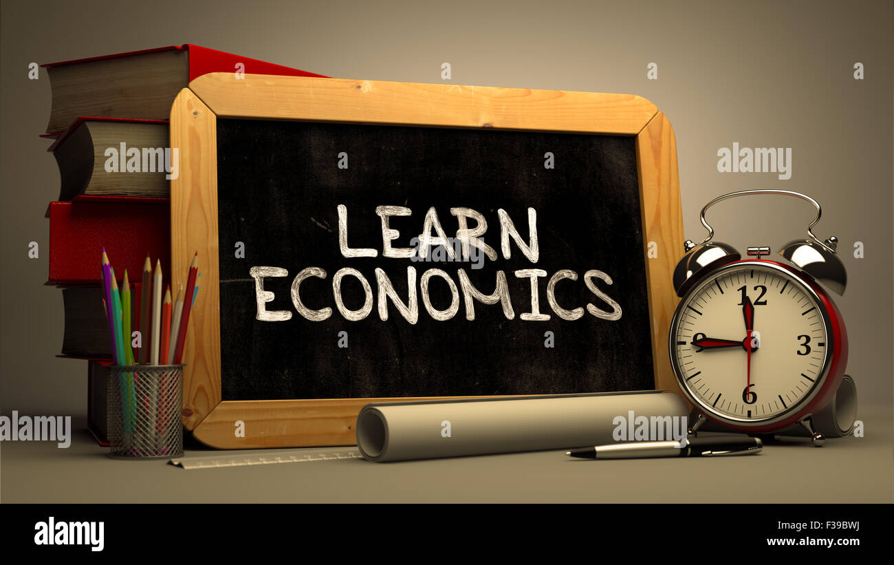 Learn Economics. Motivational Quote Handwritten by white Chalk on a Blackboard. Composition with Small Chalkboard and Stack of B Stock Photo