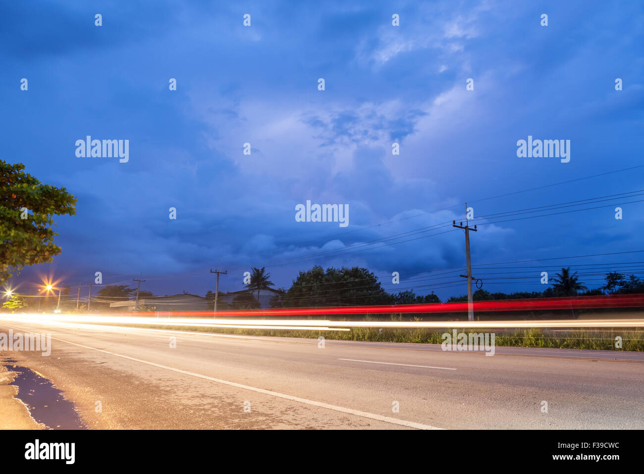 dark cloudy with lightning and light rays in the foreground of the road, Stock Photo