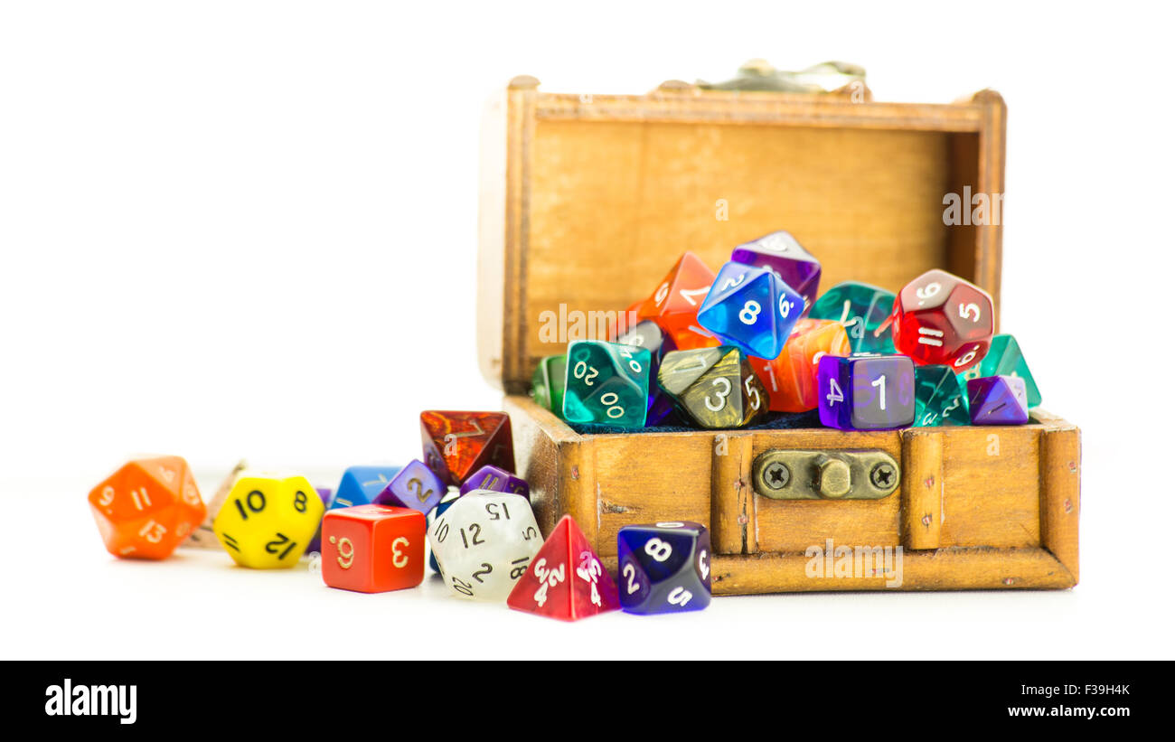 A small wooden chest overflows with multicolored dice Stock Photo