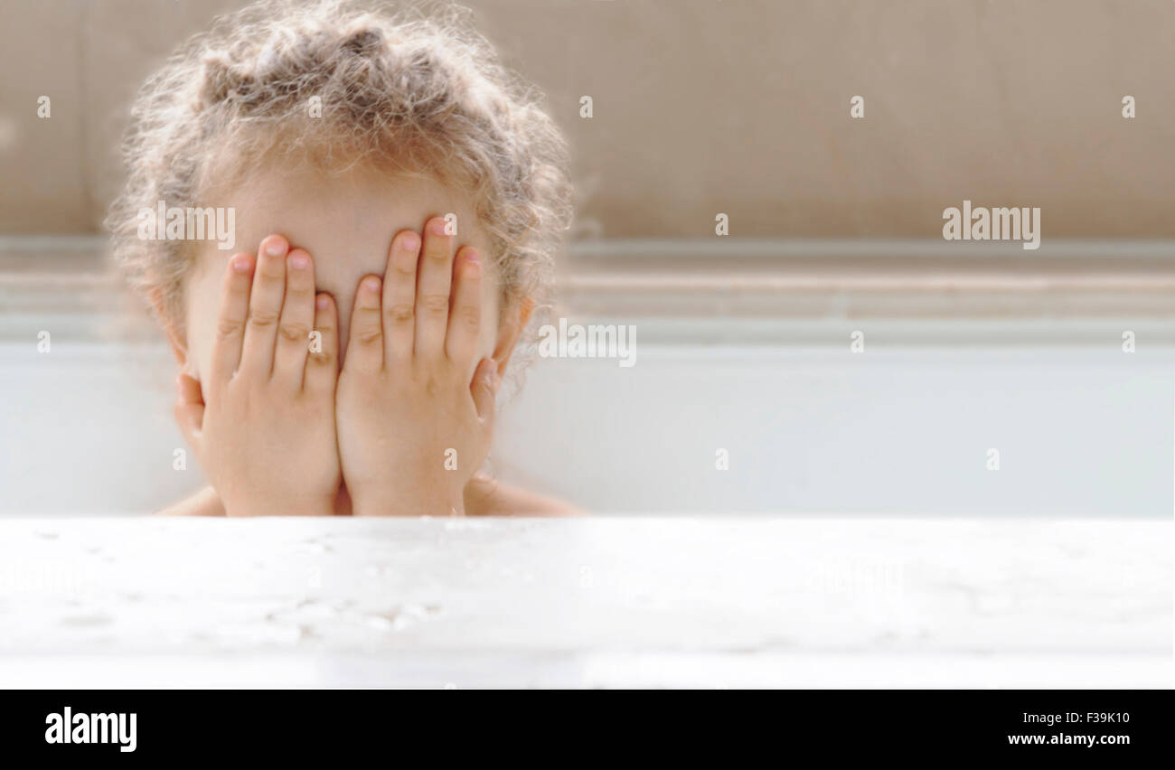 Portrait of a girl sitting in a bath covering face with her hands Stock Photo