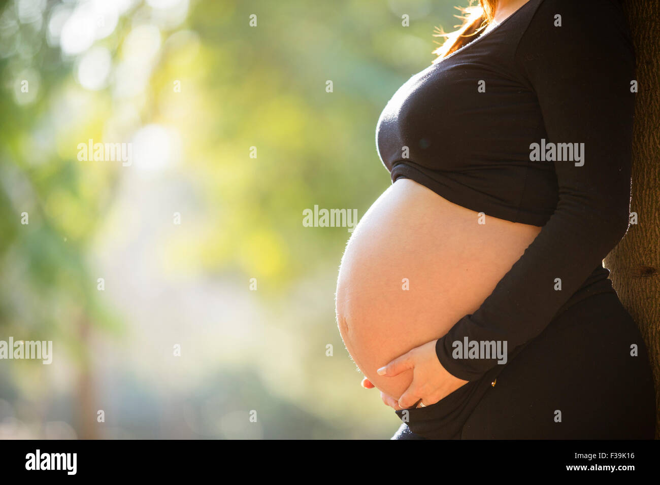Close-up of a pregnant woman standing in the park at sunset Stock Photo