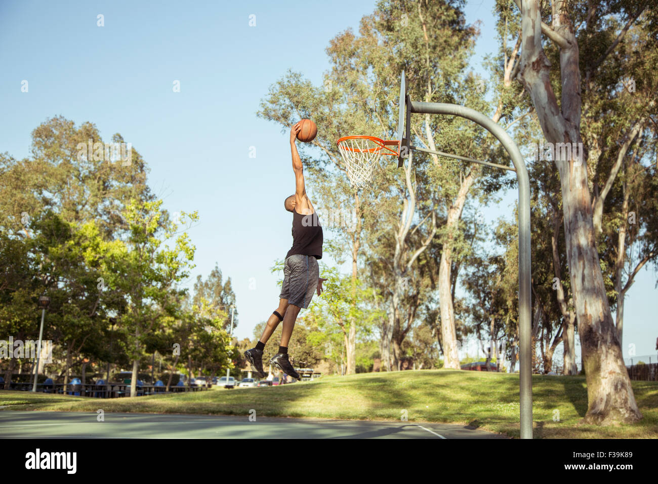 Man shooting basketball hoops in the park at sunset Stock Photo Alamy