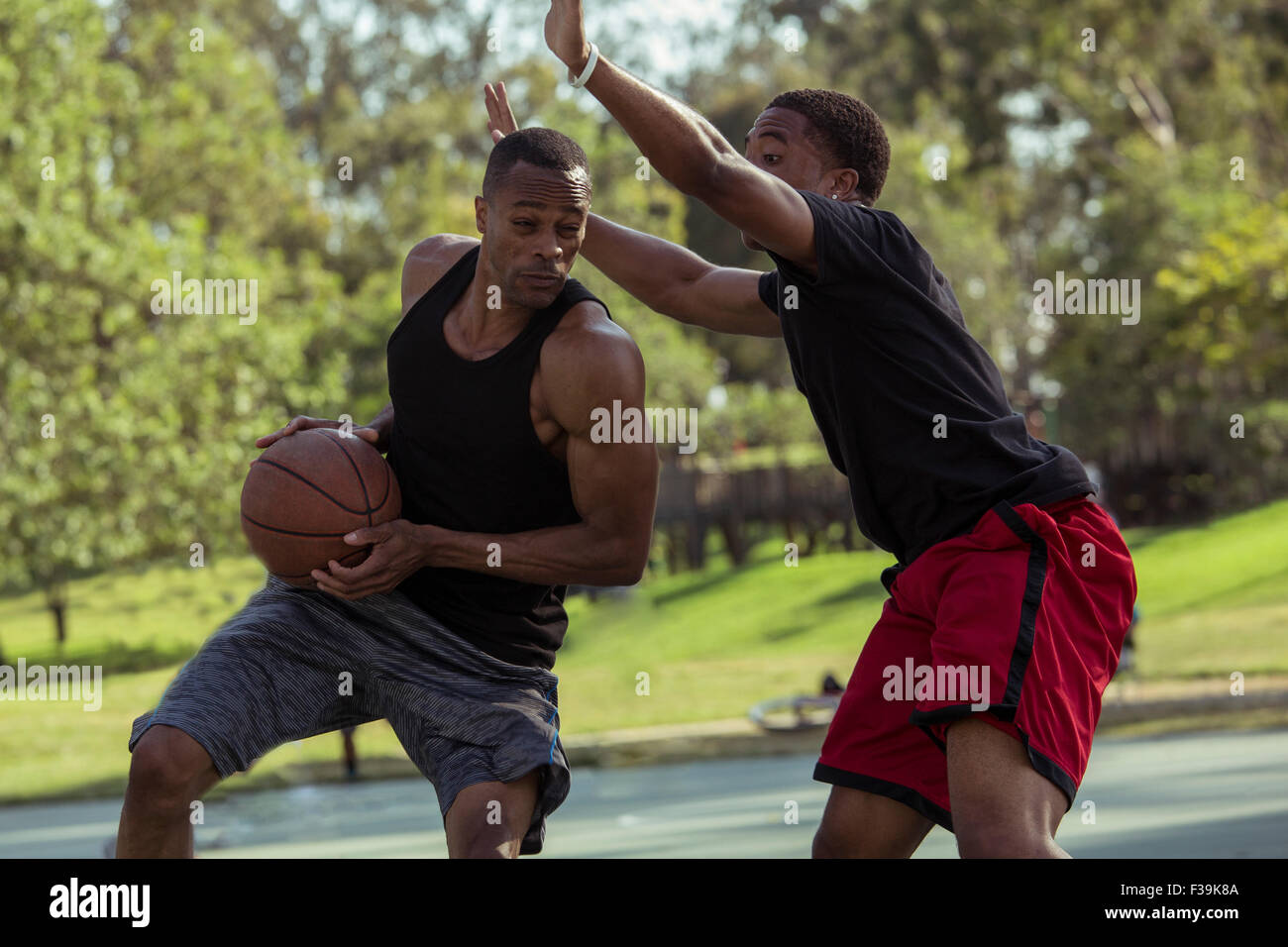 Two young men playing basketball in the park at sunset Stock Photo Alamy