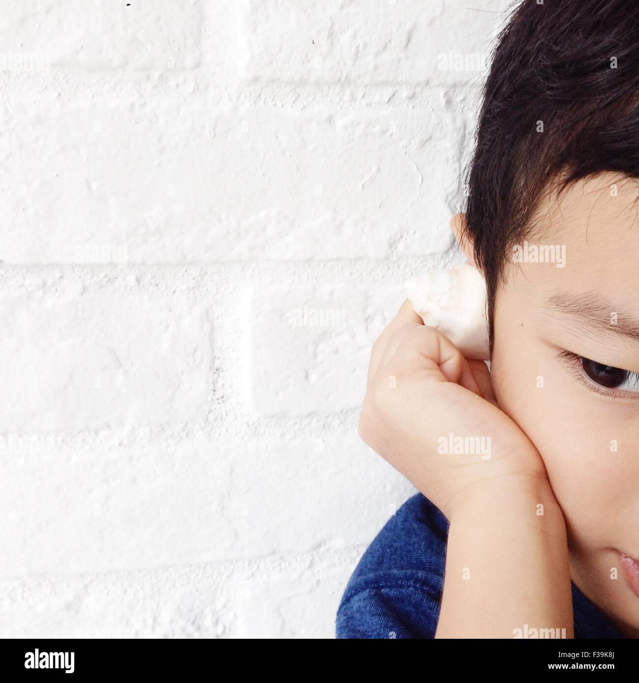 Boy listening to the sea in a tiny seashell Stock Photo