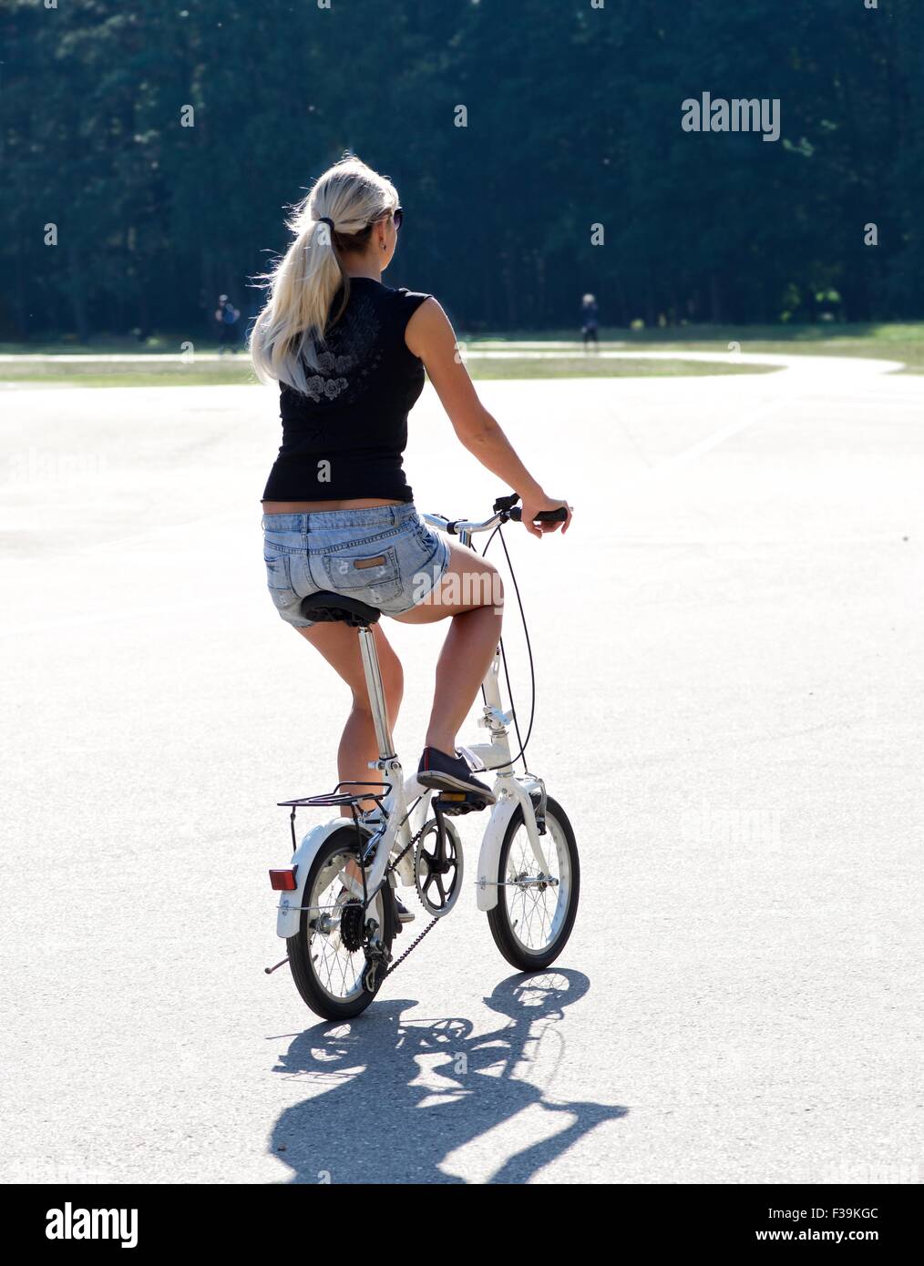 Rear view of a woman riding bicycle in the park, Lithuania Stock Photo