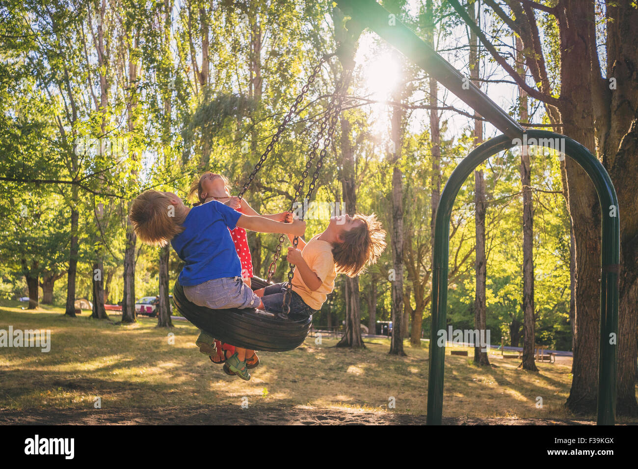 Three children playing on a swing Stock Photo