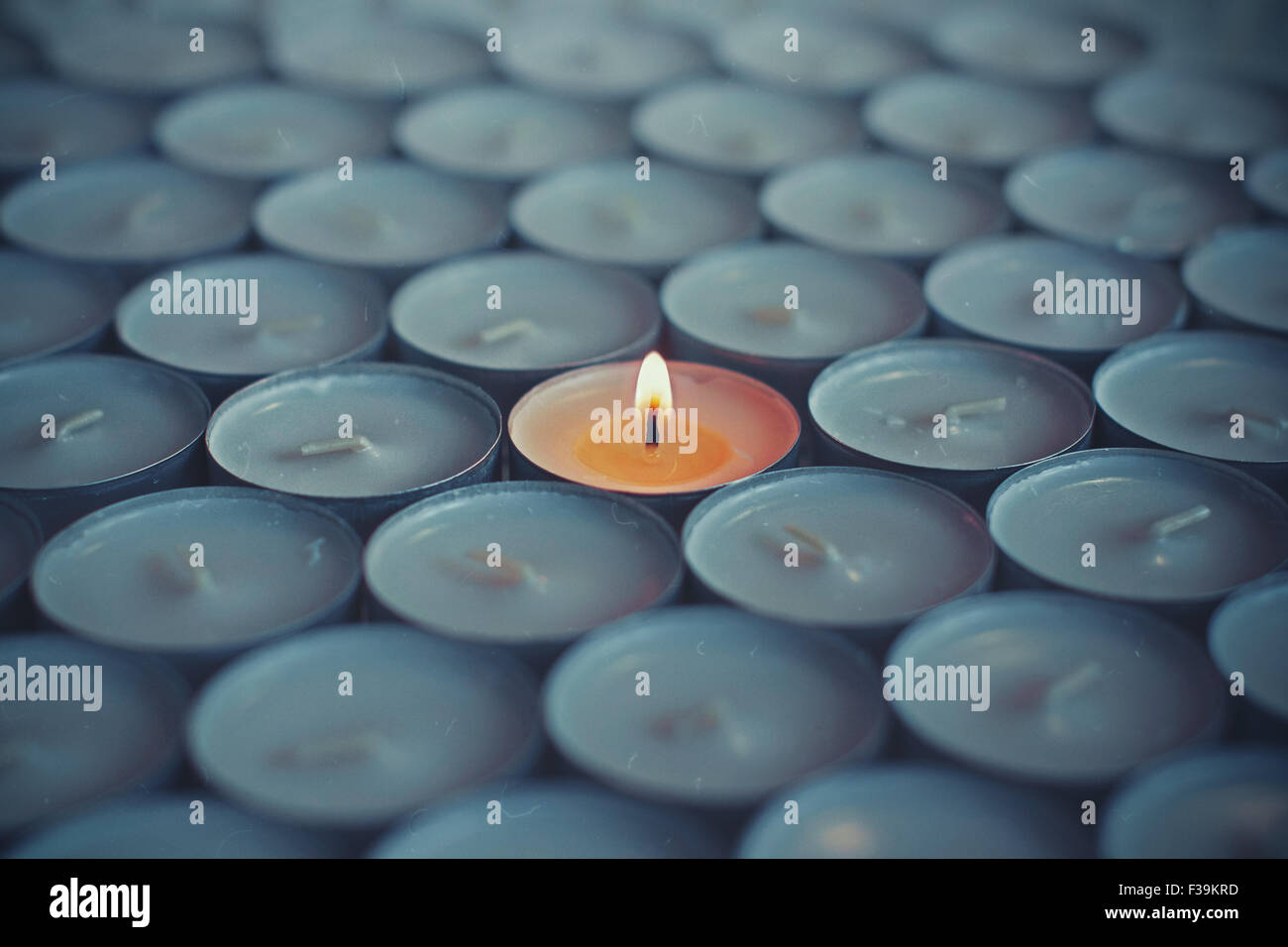 Close-up of one lit tea light surrounded by other tea lights Stock Photo