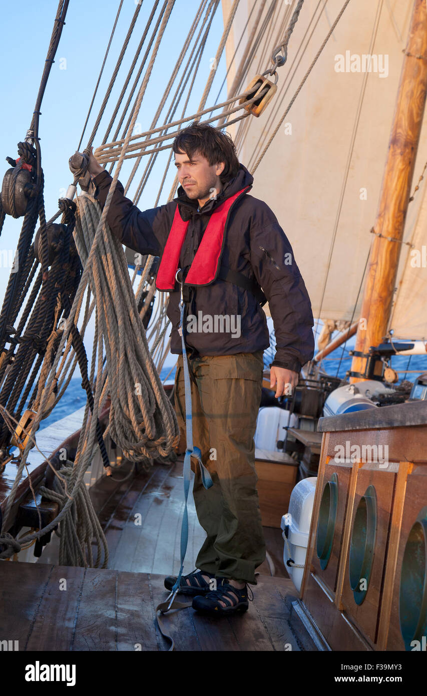 Young sailor onboard with sails behind him Stock Photo
